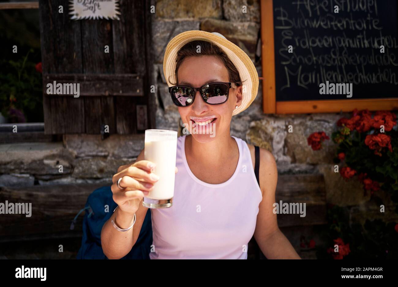 Frau, die ein Glas Buttermilch in einer Berghütte, Passeiertal, Südtirol, Italien genießt Stockfoto