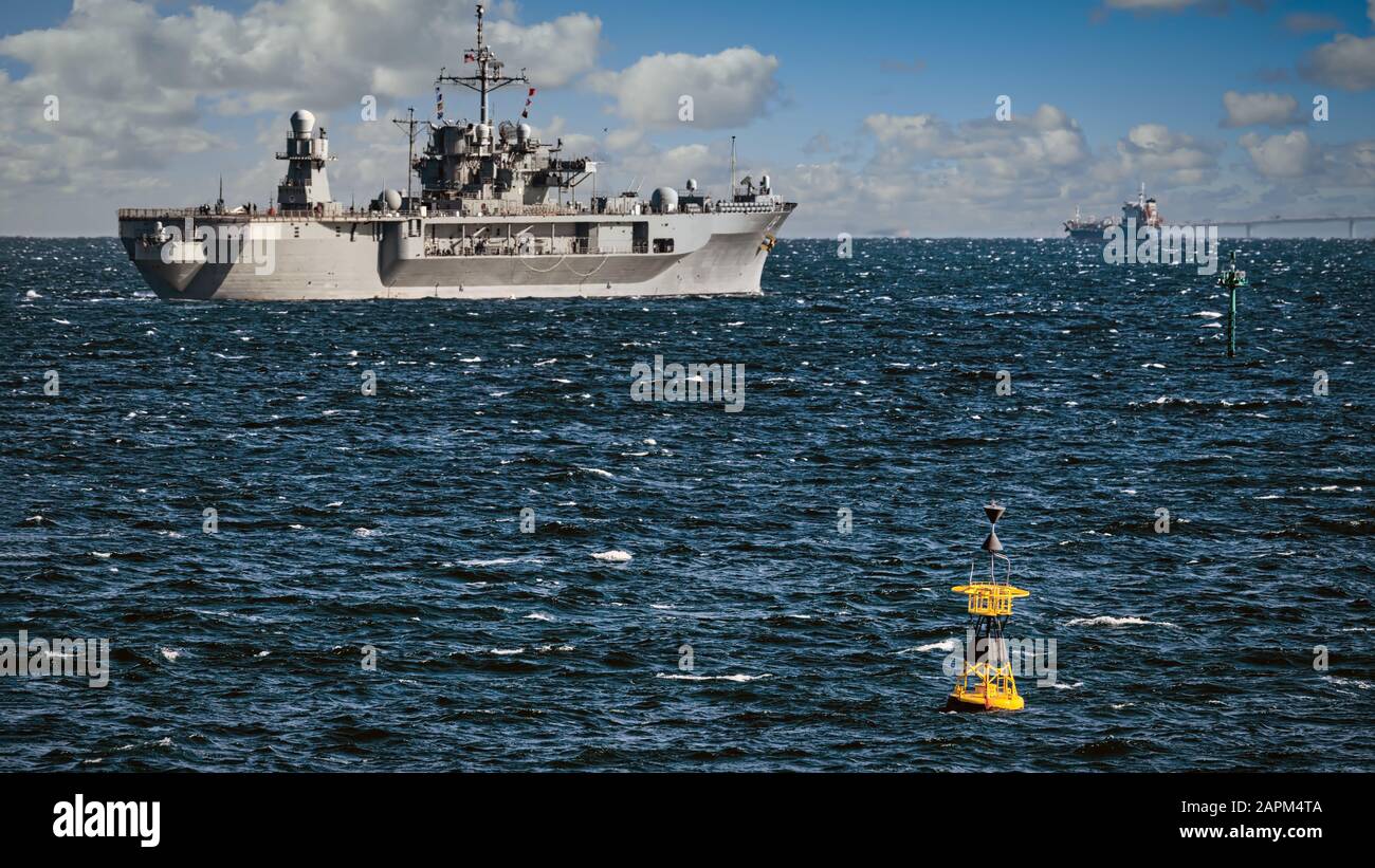 Eine gelbe Boje befindet sich in der Tokioter Bucht vor der Küste von Yokosuka, Japan, mit einem Schiff der US Navy, das auf See aufgeht. Stockfoto