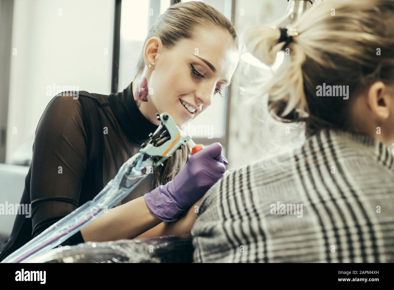 Tätooistische Frauen, die den Oberarm der weiblichen Kundin tätowieren Stockfoto