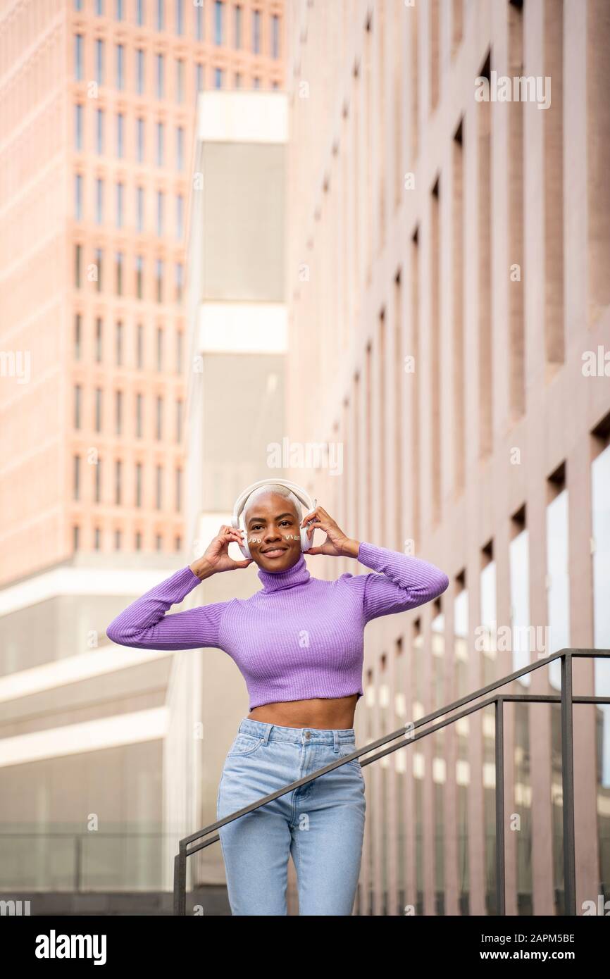 Porträt der weißen Frau mit weißen Kopfhörern, die Musik hören und in der Stadt tanzen Stockfoto