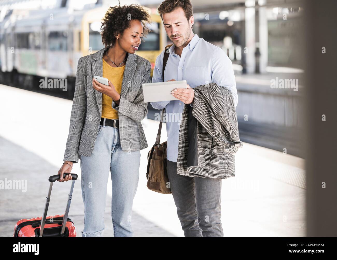 Junger Geschäftsmann und Geschäftsfrau, die zusammen Tablett am Bahnhof nutzen Stockfoto