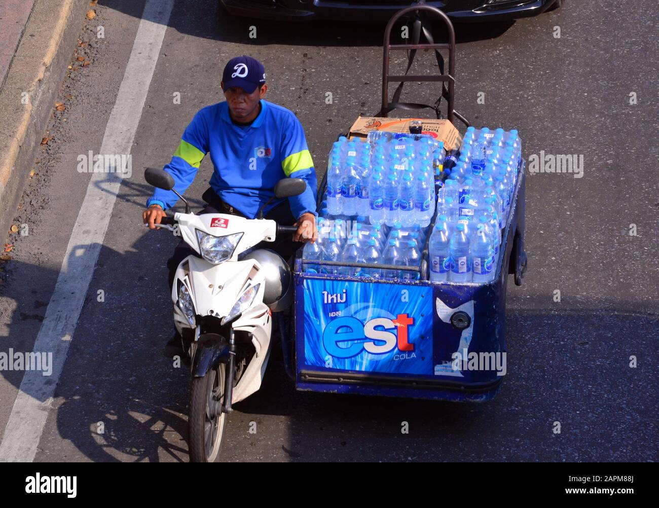 Ein Blick über den Kopf eines Mannes, der mit einem Motorrad in der Innenstadt von Bangkok, Thailand und Asien Wasserflaschen transportiert Stockfoto