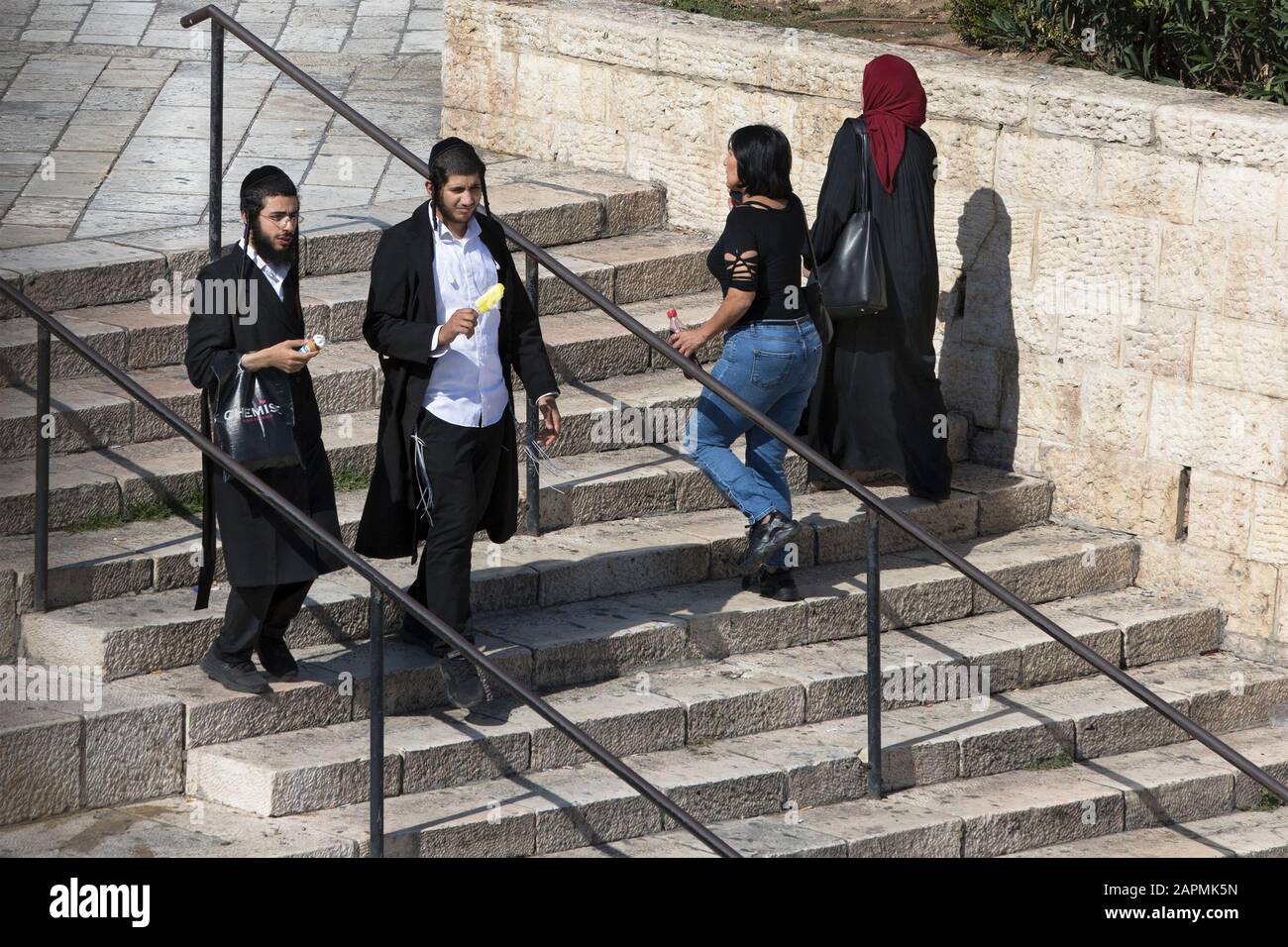 Fußgänger auf den Stufen, die zum Damaszener Tor der Altstadt von Jerusalem hinabgehen, mit zwei ultraorthodoxen jüdischen Männern, die Eis und Päpste essen Stockfoto