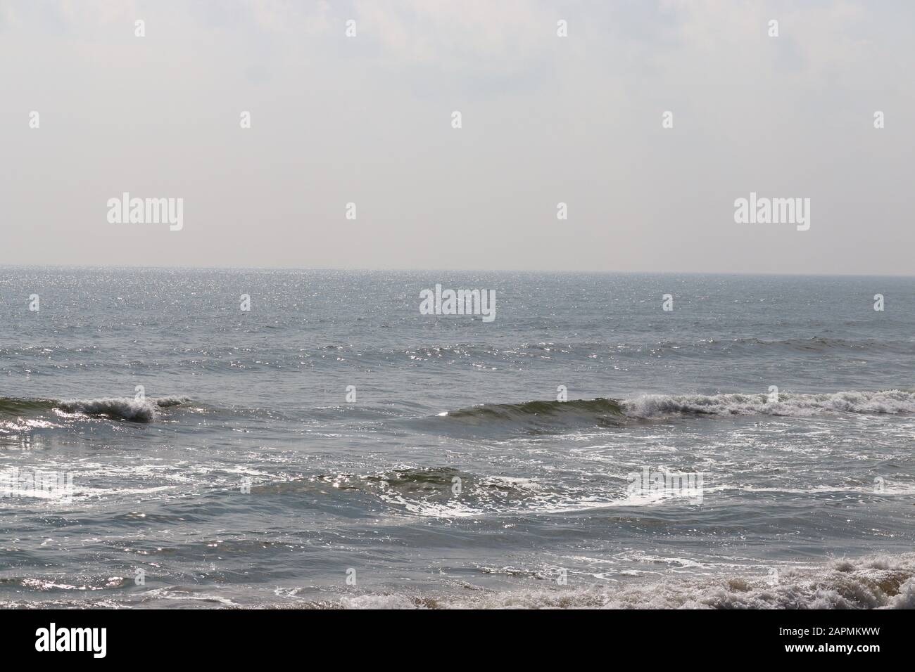 Abstrakter Unschärfe-Hintergrund, Natur des tropischen Sommerstandes mit Sonnenstrahlen. Goldener Sandstrand, Meerwasser gegen blauen Himmel mit weißen Wolken. Cop Stockfoto