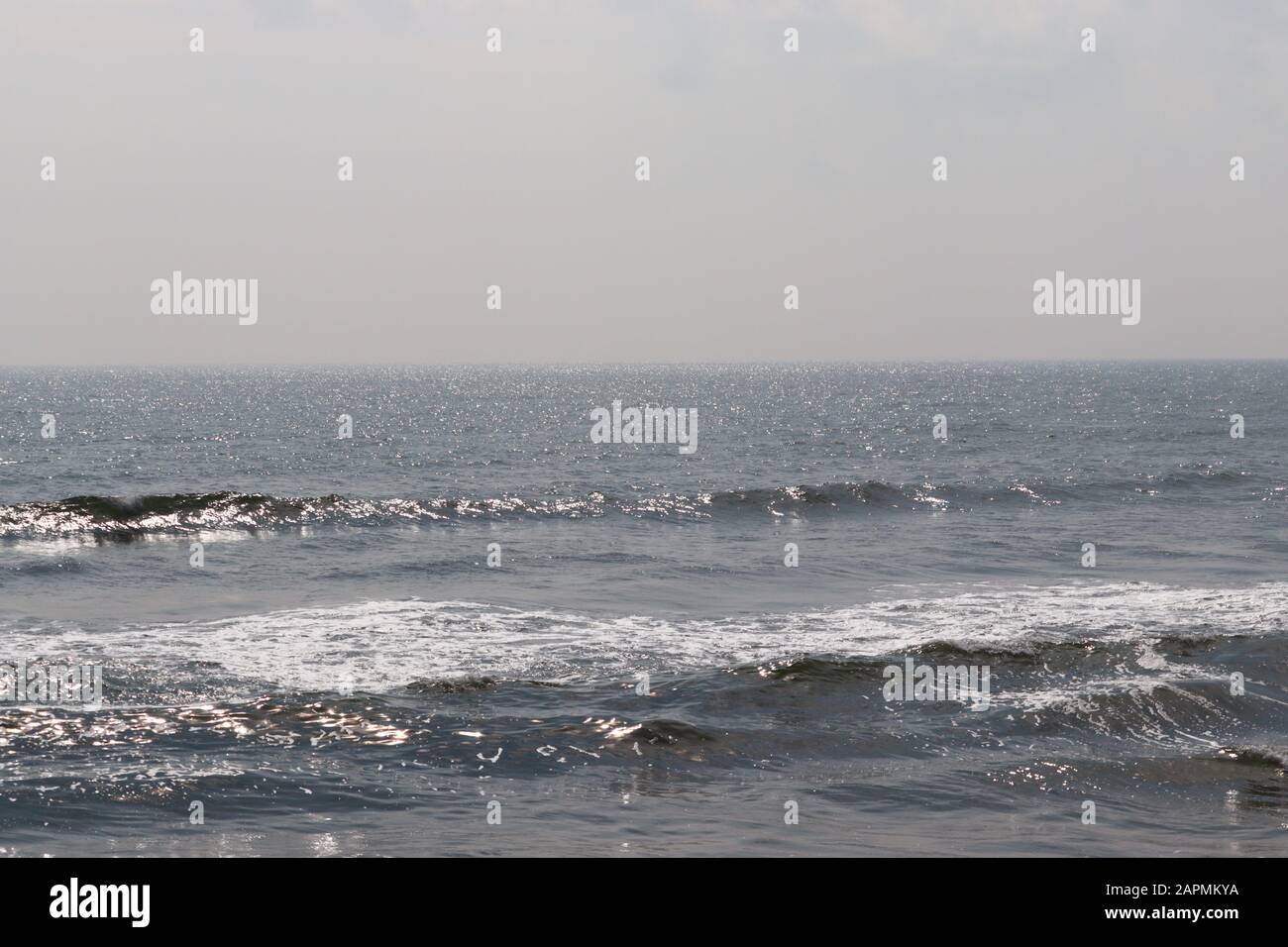 Abstrakter Unschärfe-Hintergrund, Natur des tropischen Sommerstandes mit Sonnenstrahlen. Goldener Sandstrand, Meerwasser gegen blauen Himmel mit weißen Wolken. Cop Stockfoto