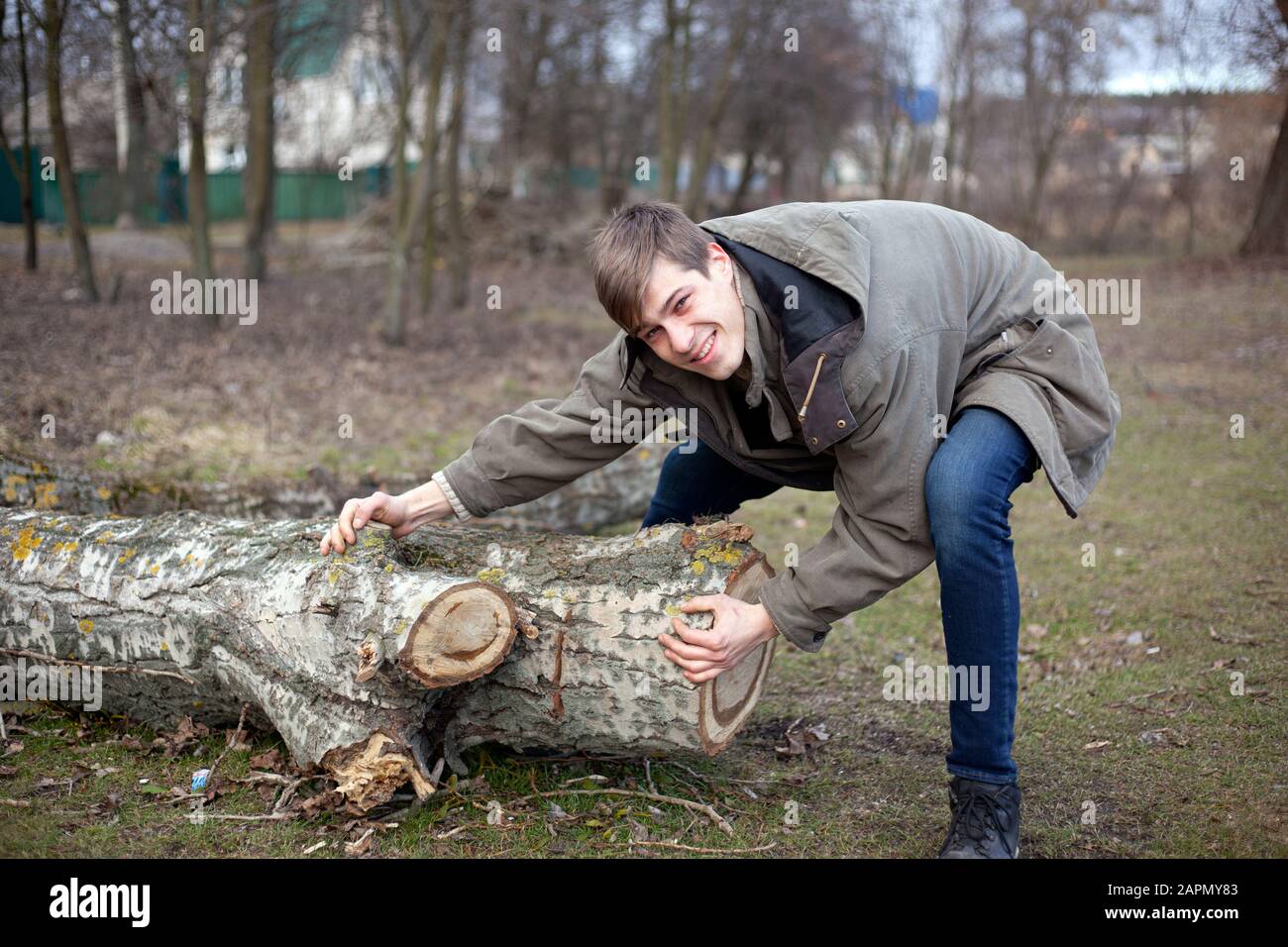 Waldreinigungshelfer, die sich um die Natur kümmern. Ein Kerl versucht zu ziehen, um einen umgestürzten Baum zu verschieben. Stockfoto