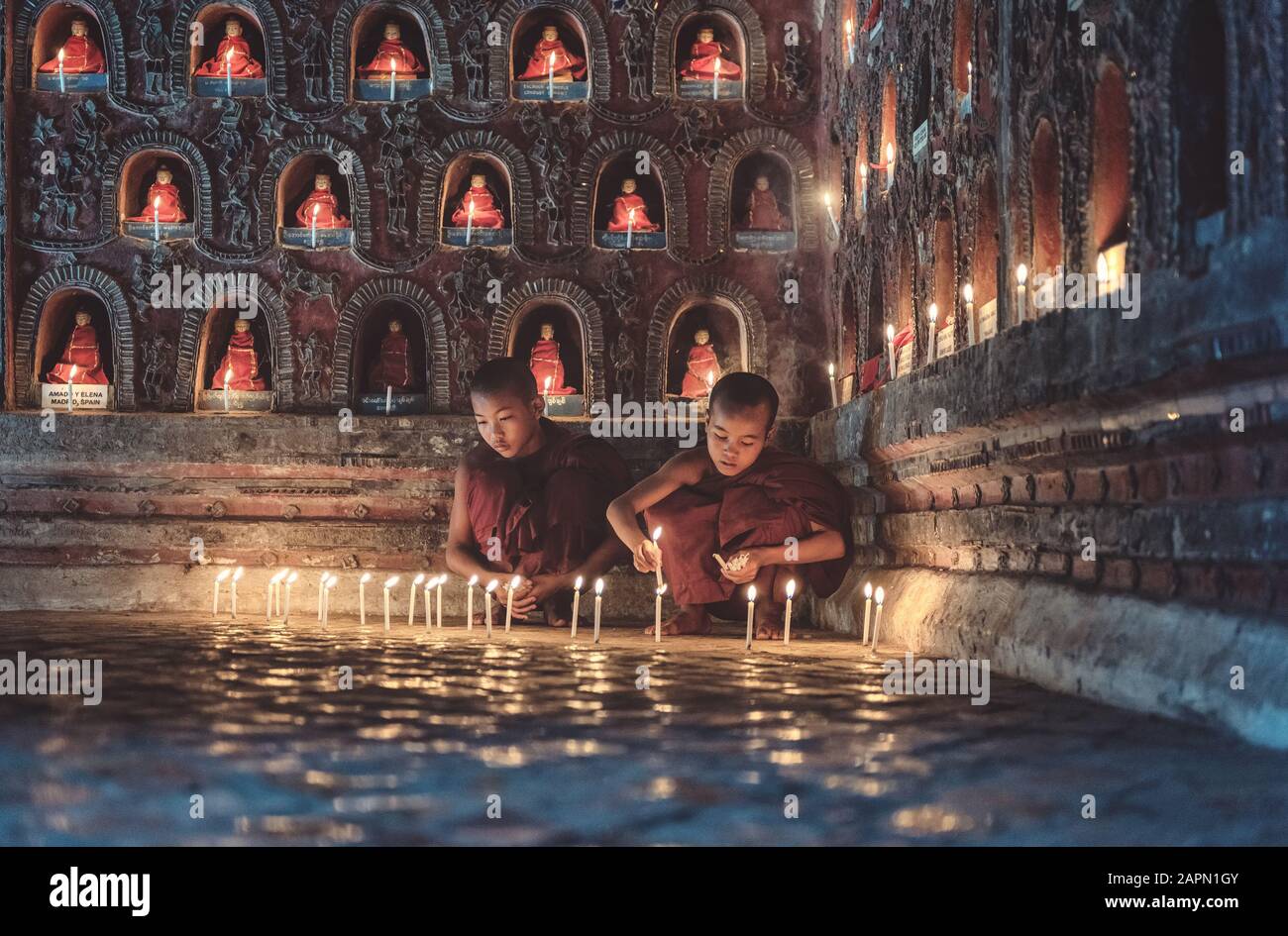 Junge Anfängermönche beleuchten Kerzenlicht in einem buddhistischen Tempel, in der Low-Light-Umgebung, im Shan-Staat, in Myanmar. Stockfoto