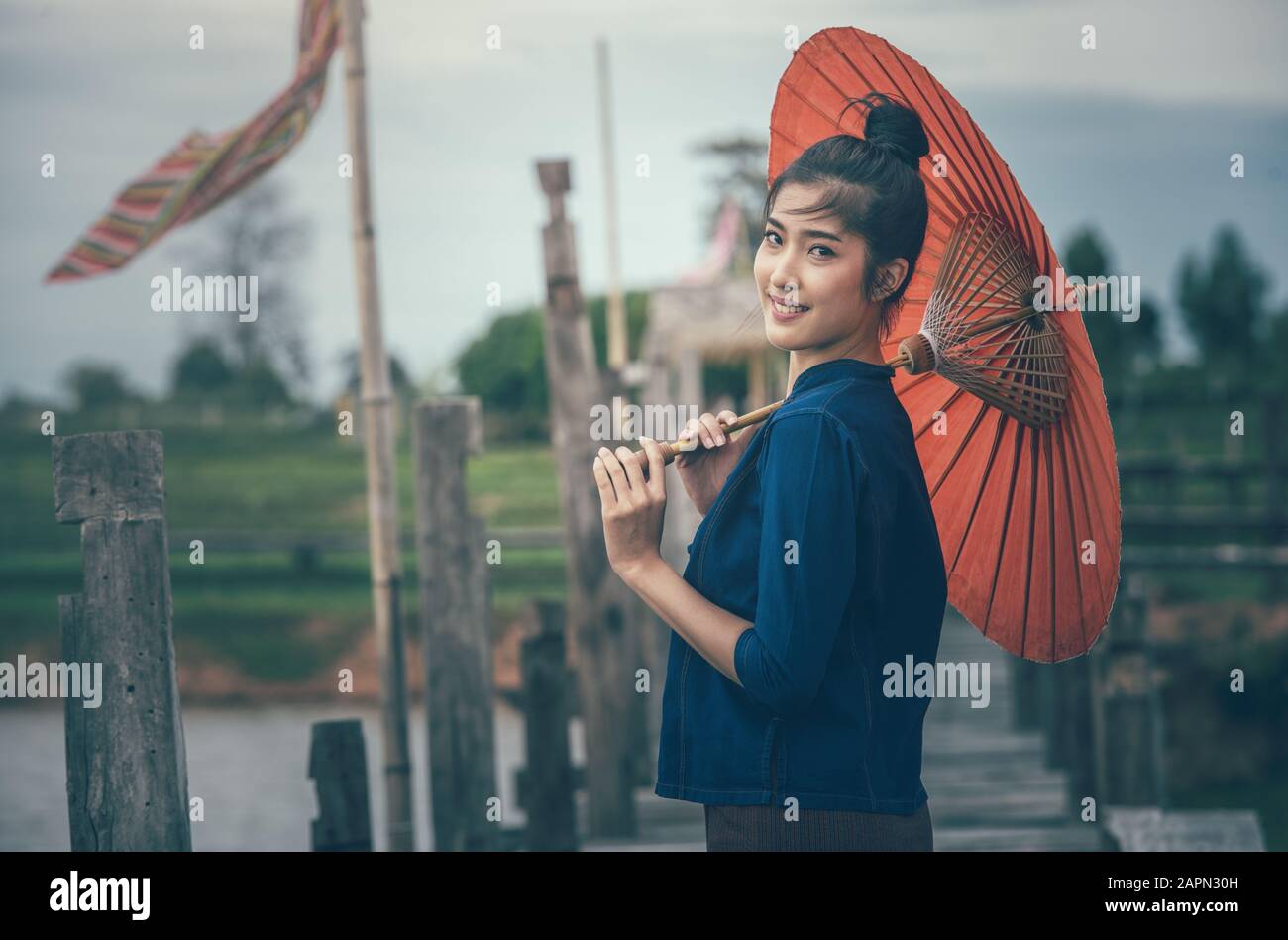 Asiatische Mädchen tragen traditionelle Kleidung Halten den roten Regenschirm auf dem Land, Schöne asiatische Frauen Stockfoto