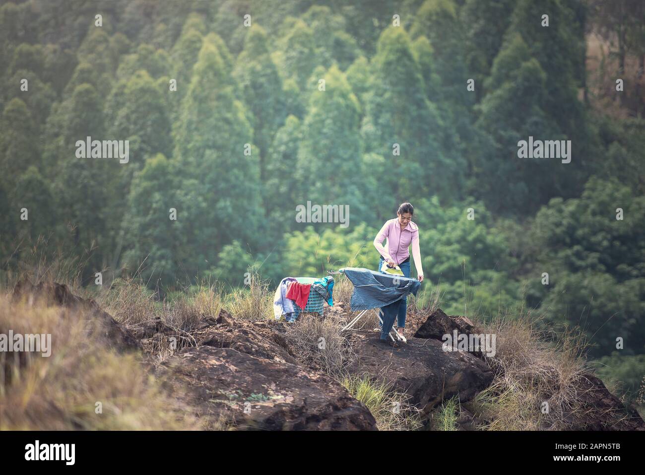Junge Frau bügelt an Klippen in der Natur, Arbeitslebenkonzept Geht Aus Stockfoto