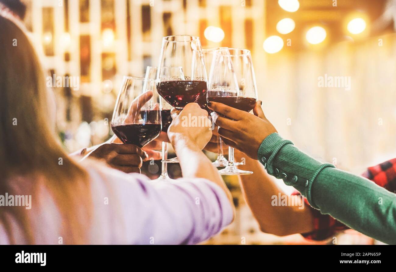Eine Gruppe von Freunden jubelt mit Rotwein in der Vintage-Bar für eine Happy Hour - junge Leute haben Spaß damit, Vorspeisen zu genießen, die im trendigen Restaurant sitzen Stockfoto
