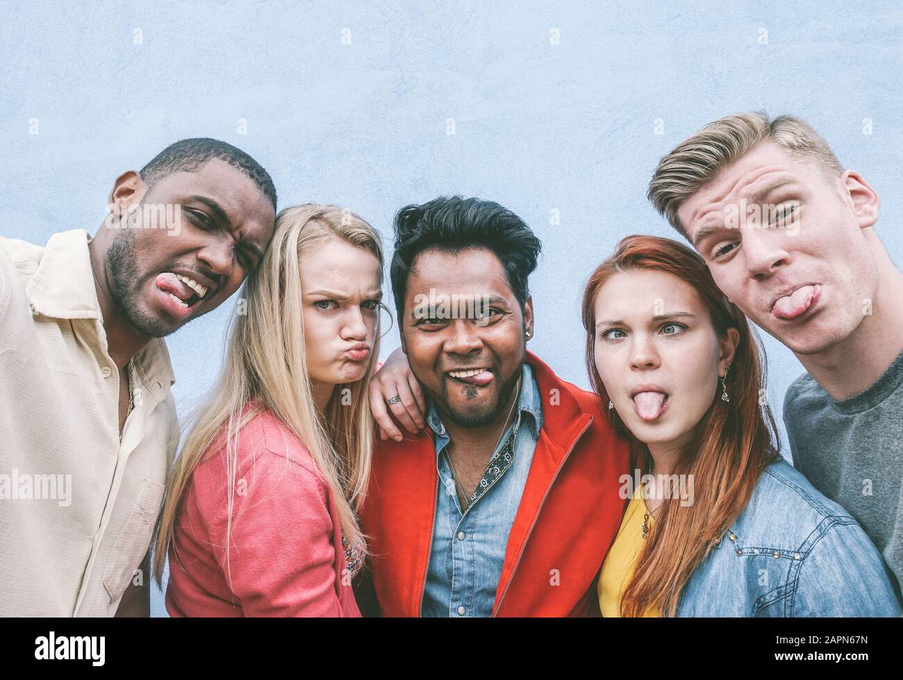Fröhliche Freunde aus verschiedenen Kulturen und Rassen machen lustige Gesichter in der Smartphone-Kamera - Jugend- und Freundschaftskonzept - Kontrastfilter Stockfoto
