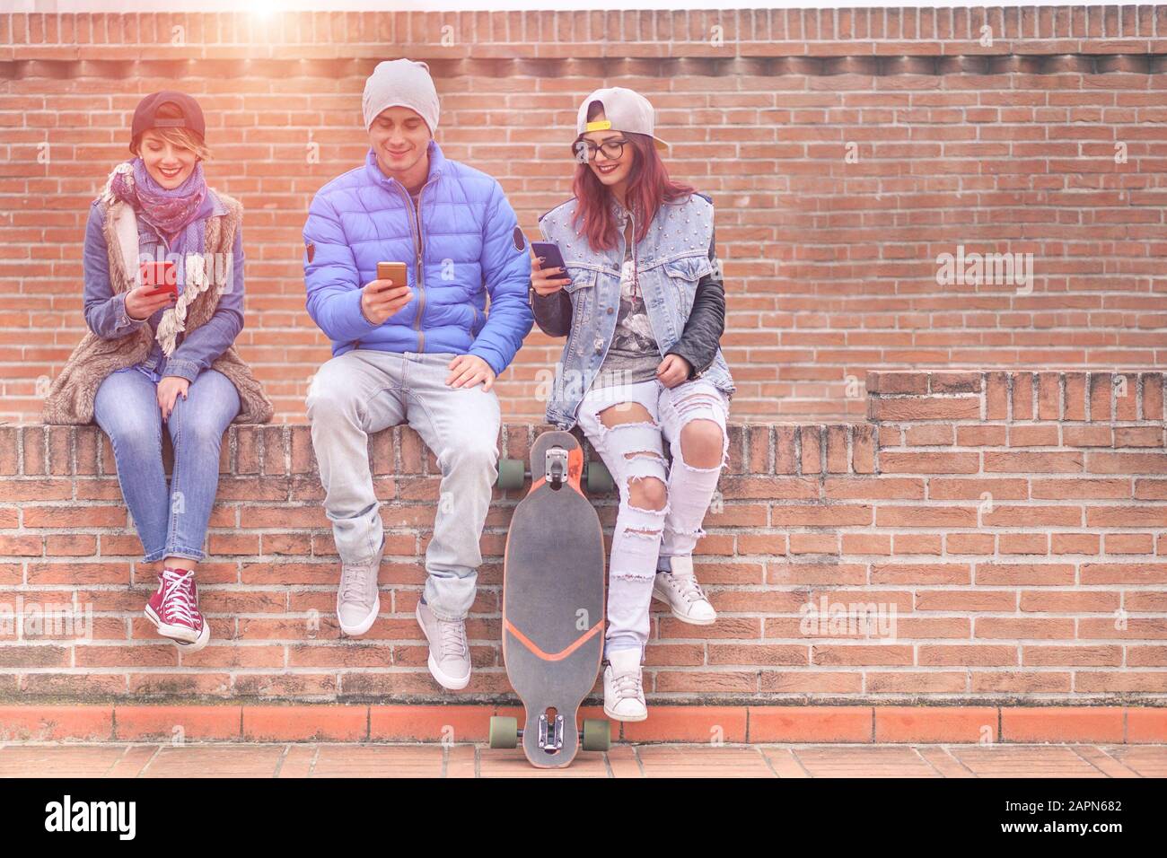 Gruppe junger Freunde, die online mit Smartphones im Freien spielen - Fröhliche Trend-Leute sind abhängig vom mobilen - Technologie- und Modekonzept in der Stadt Stockfoto