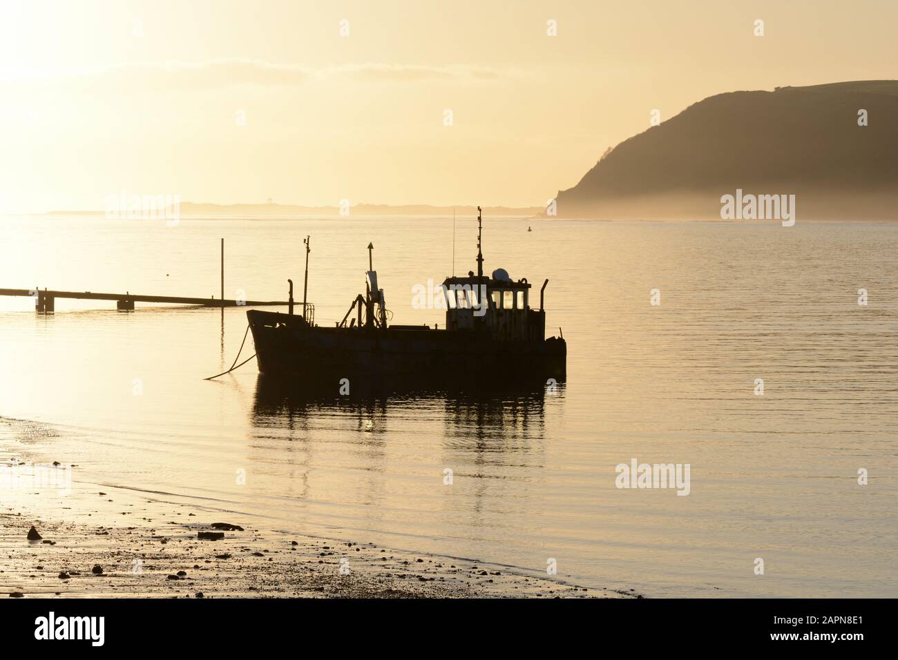 Altes Fischerboot Silhouette in nebligen frühen Abendstunden leichten Sonnenuntergang Tywi Estuary Ferryside Carmarthenshire Wales Cymru UK Stockfoto