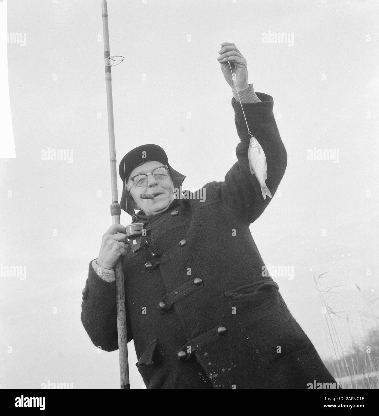 Association Club der Hundert (Fisch); Mann mit Zigarre im Mund und Angelrute in der Hand, während er seinen Fang zeigt Datum: 16. Dezember 1965 Schlüsselwörter: Angeln, Angeln, Fischer Stockfoto