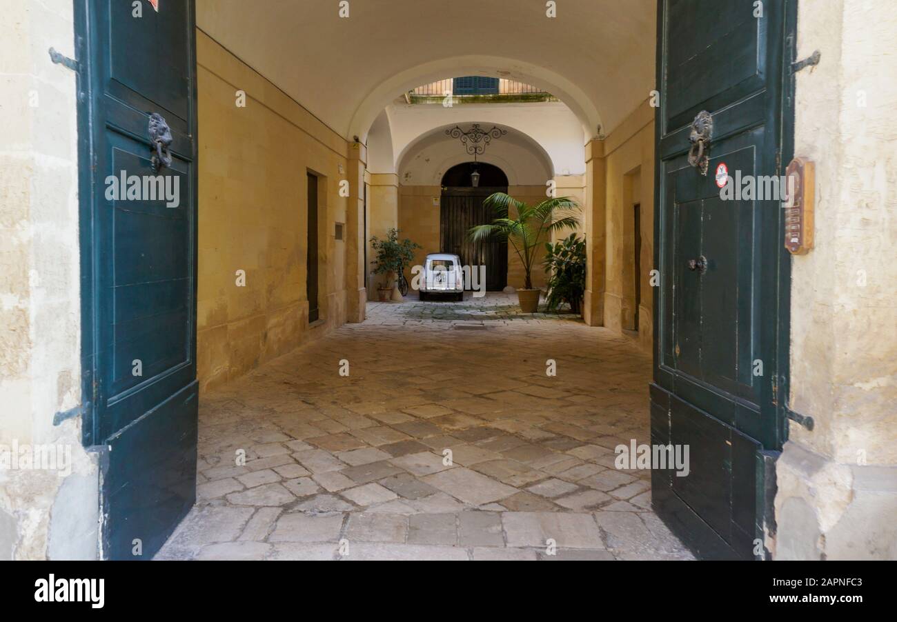 Kleines italienisches Auto in einem Innenhof durch einen Bogen Stockfoto