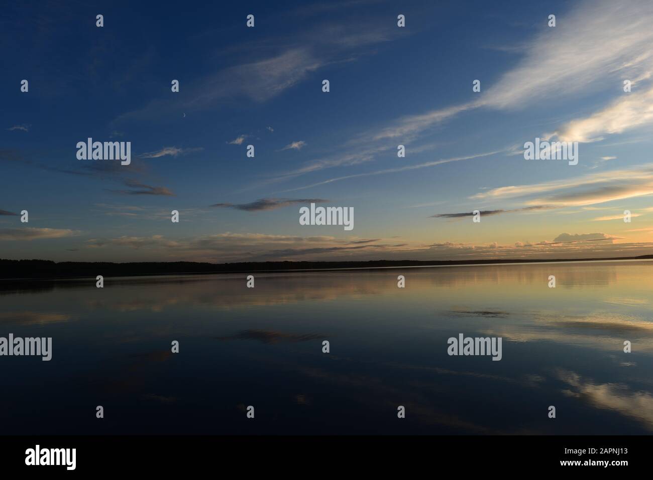 Nächtlicher, mondblauer Himmel, der sich in ruhigem Seewasser niederschlug Stockfoto