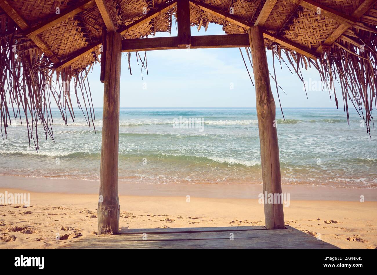 Tropischer Holzschatten am Strand, Farbtonierung angewendet, Sommerferienkonzept. Stockfoto