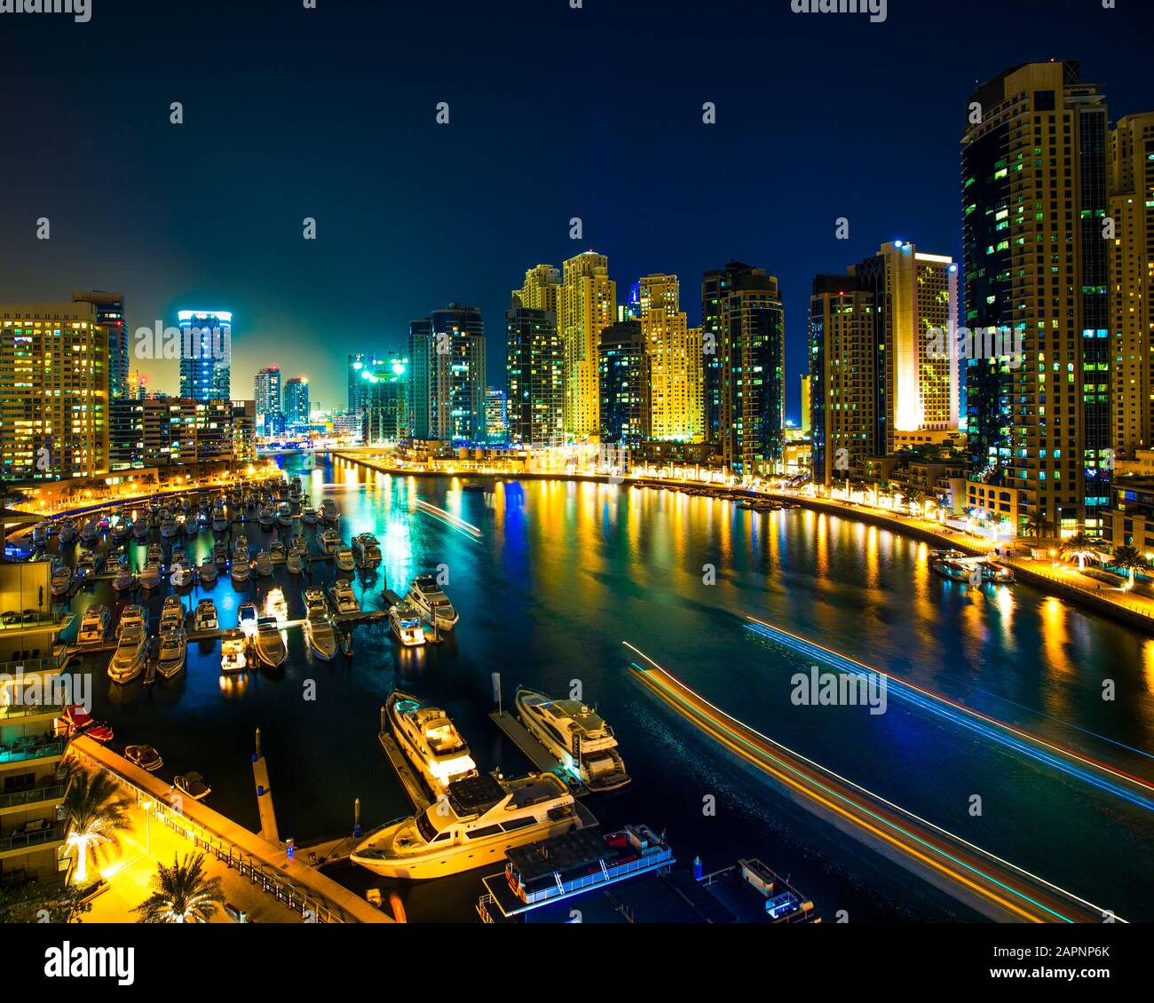 Nachtszene der Skyline der Stadt und Boote, die im Hafen von Dubai gegraben wurden Stockfoto