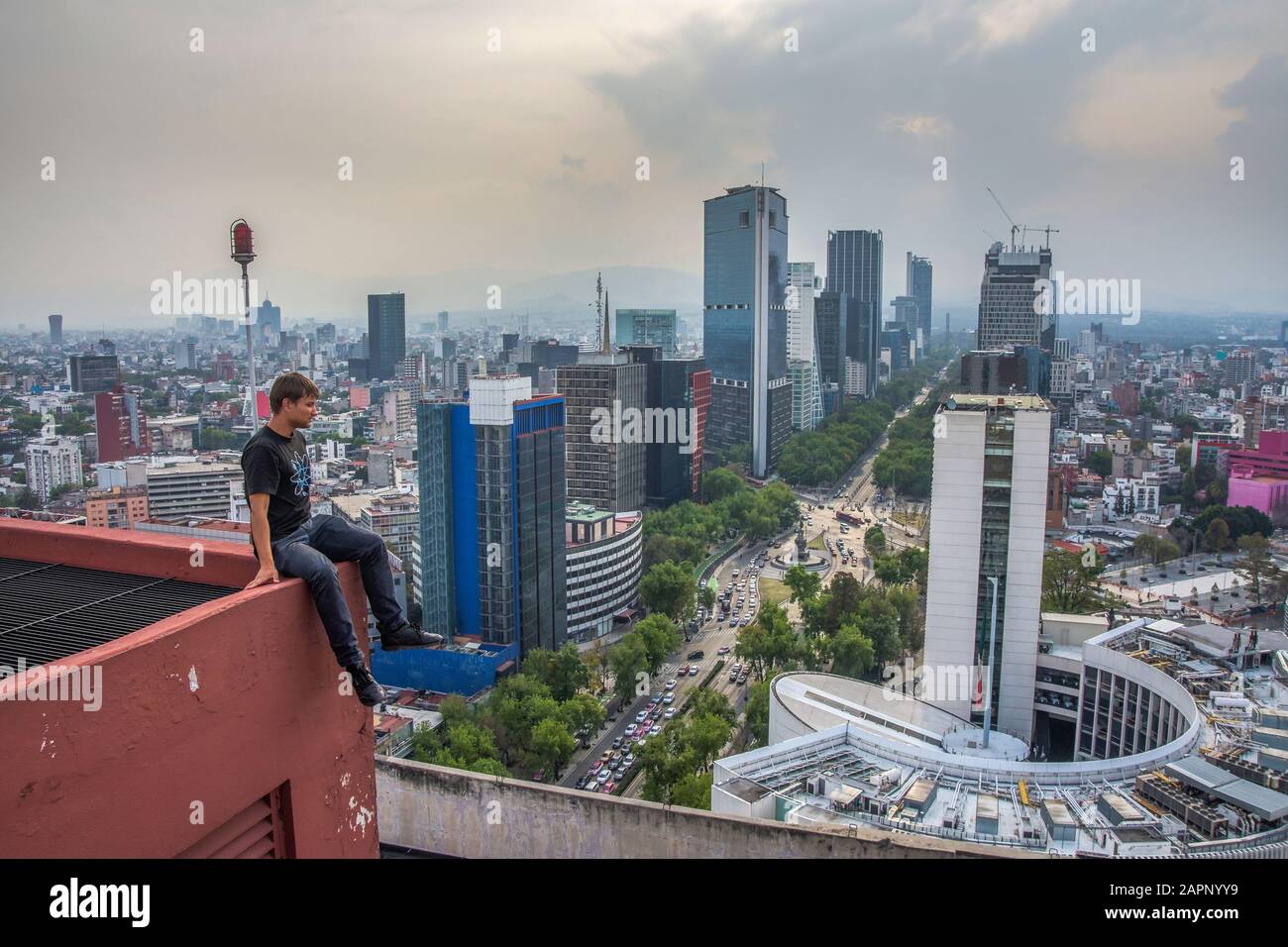 Junge Männer sittingon das Dachhaus in Mexiko-Stadt. Paseo de la Reforma Panoramaaussicht. Extreme Männer auf dem Dach Stockfoto