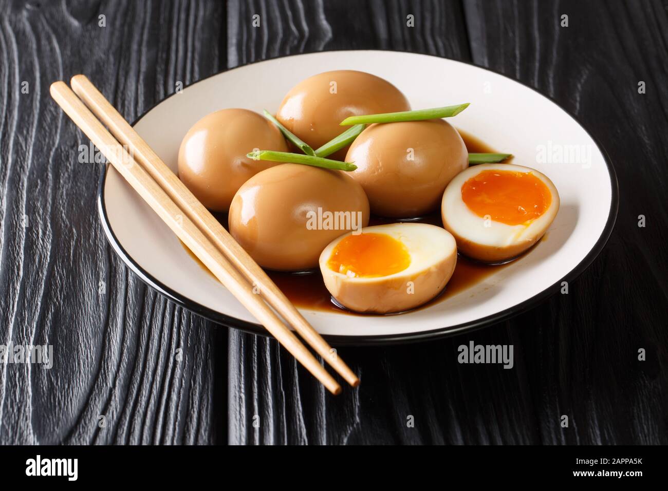 Köstlichen weich gekochten japanischen Eiern aus Nitramago in Sojamarinade mit grünen Zwiebeln in einem Teller auf dem Tisch. Horizontal Stockfoto