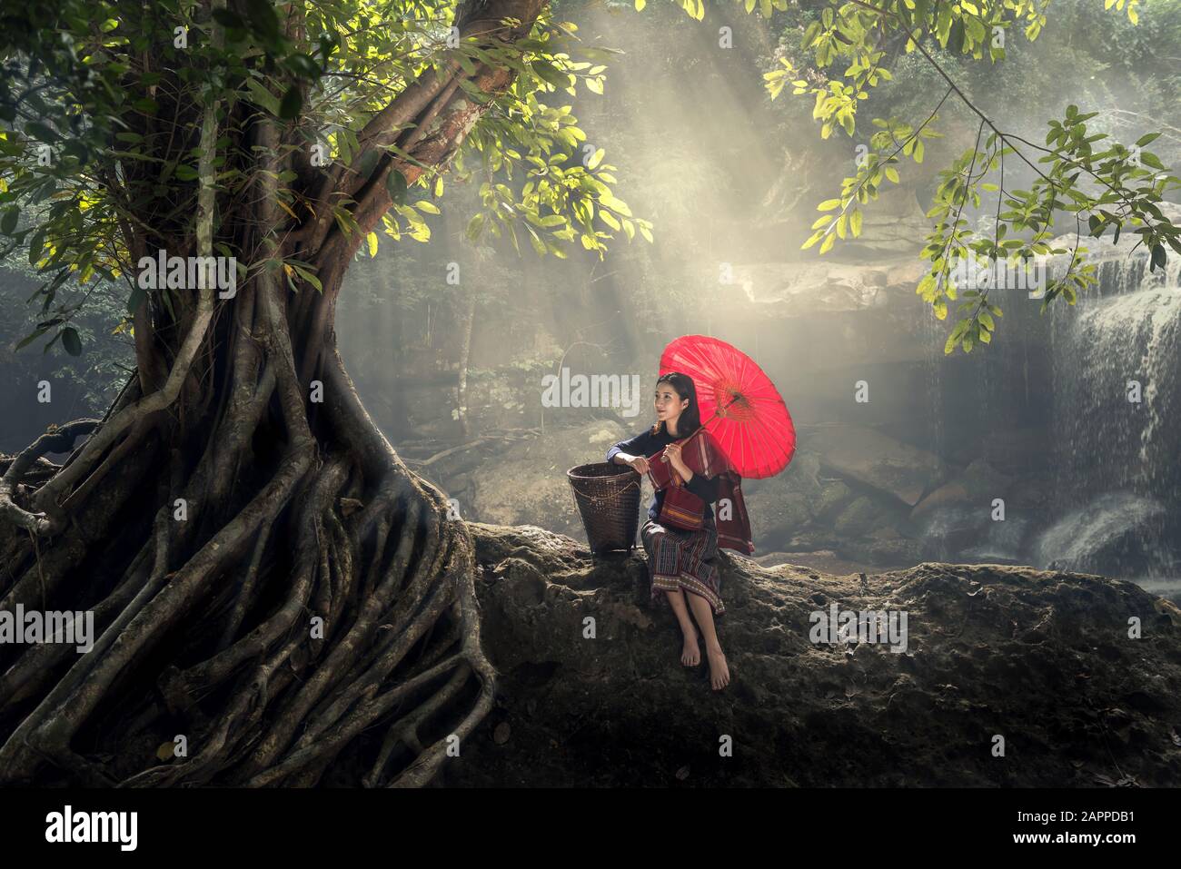 Asiatische junge Frau erholt sich in der Natur, mit rotem Regenschirm im grünen Wald. Stockfoto