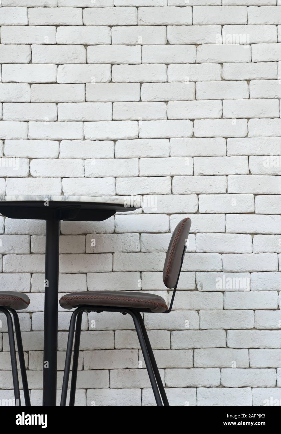 Schwarz-brauner Stuhl und Tisch mit weißem Backstein im Innenminimalismus Loft-Hintergrund Stockfoto