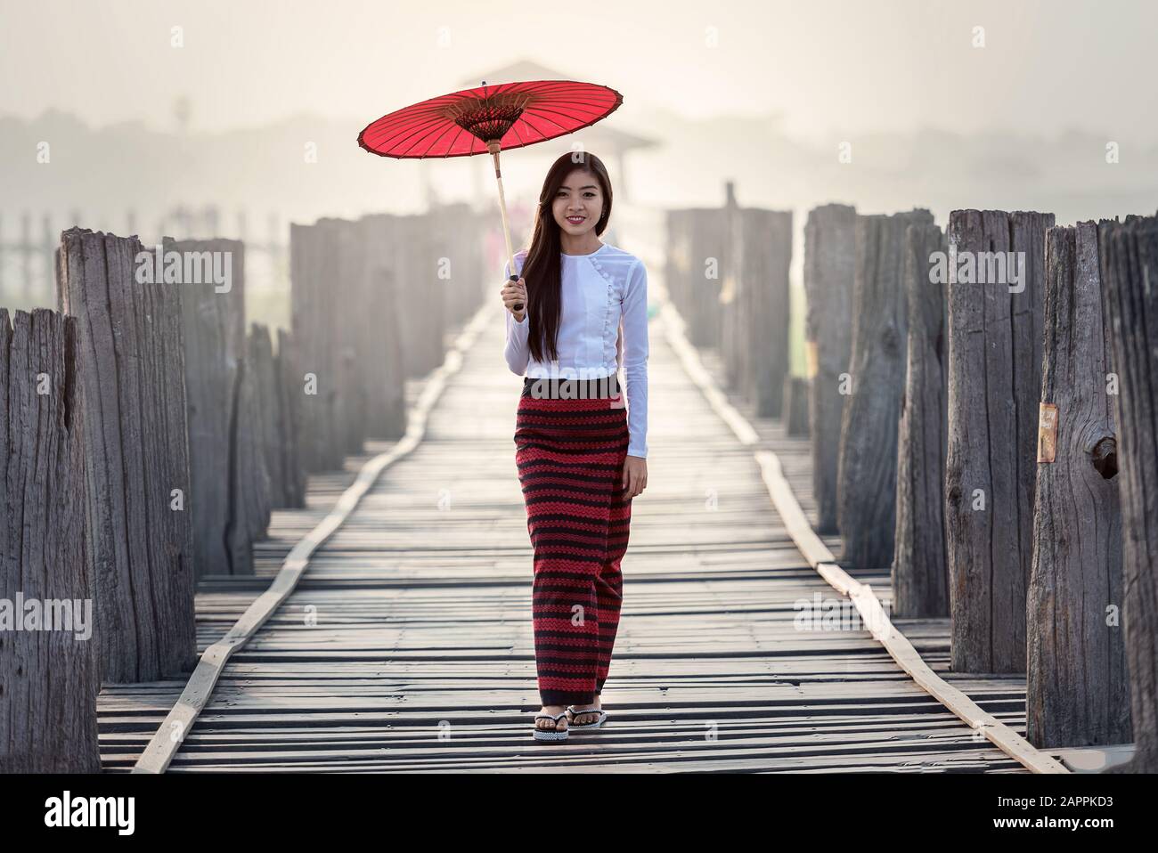 Burmesischen Frau mit traditionellen roten Schirm und Fuß auf U-Bein Brücke Stockfoto