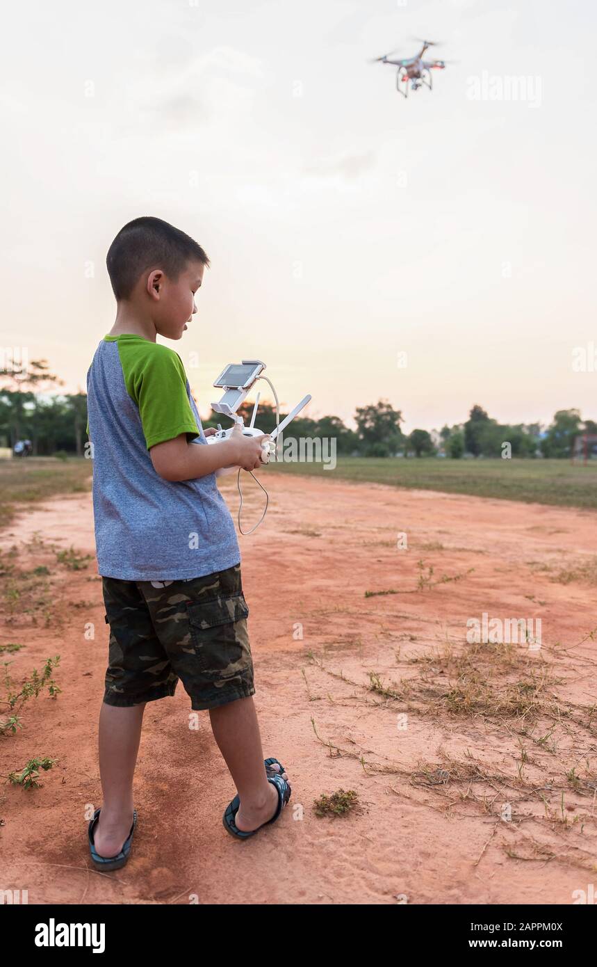 Kinderporträt mit Quadcopter-Drohne im Freien. Fröhlicher Junge, der mit fliegender Drohne mit Kamera über Smartphone spielt Stockfoto