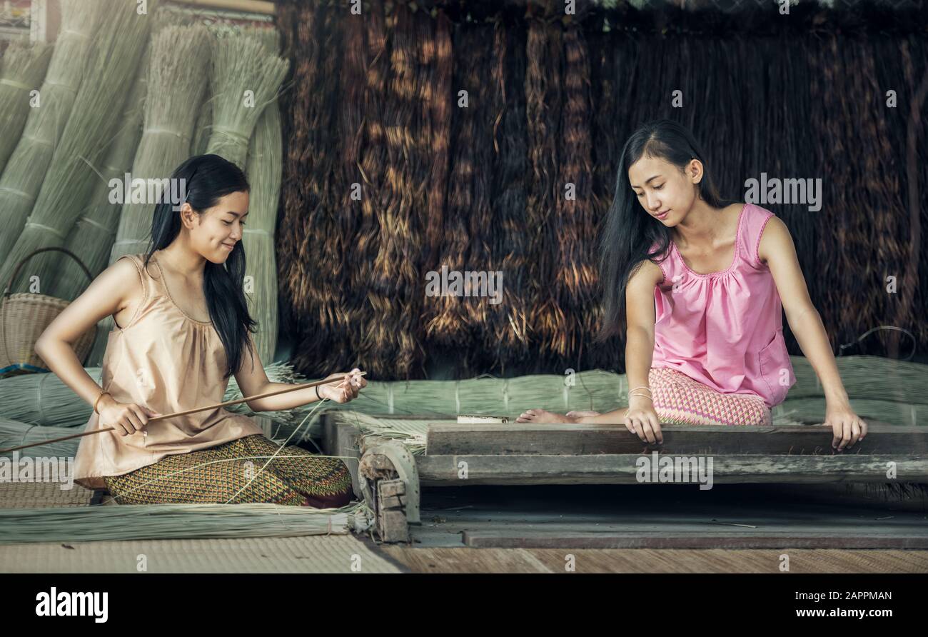 Thailändische Mädchen arbeiten Textilien mit dem Papyrus die Matte. Stockfoto