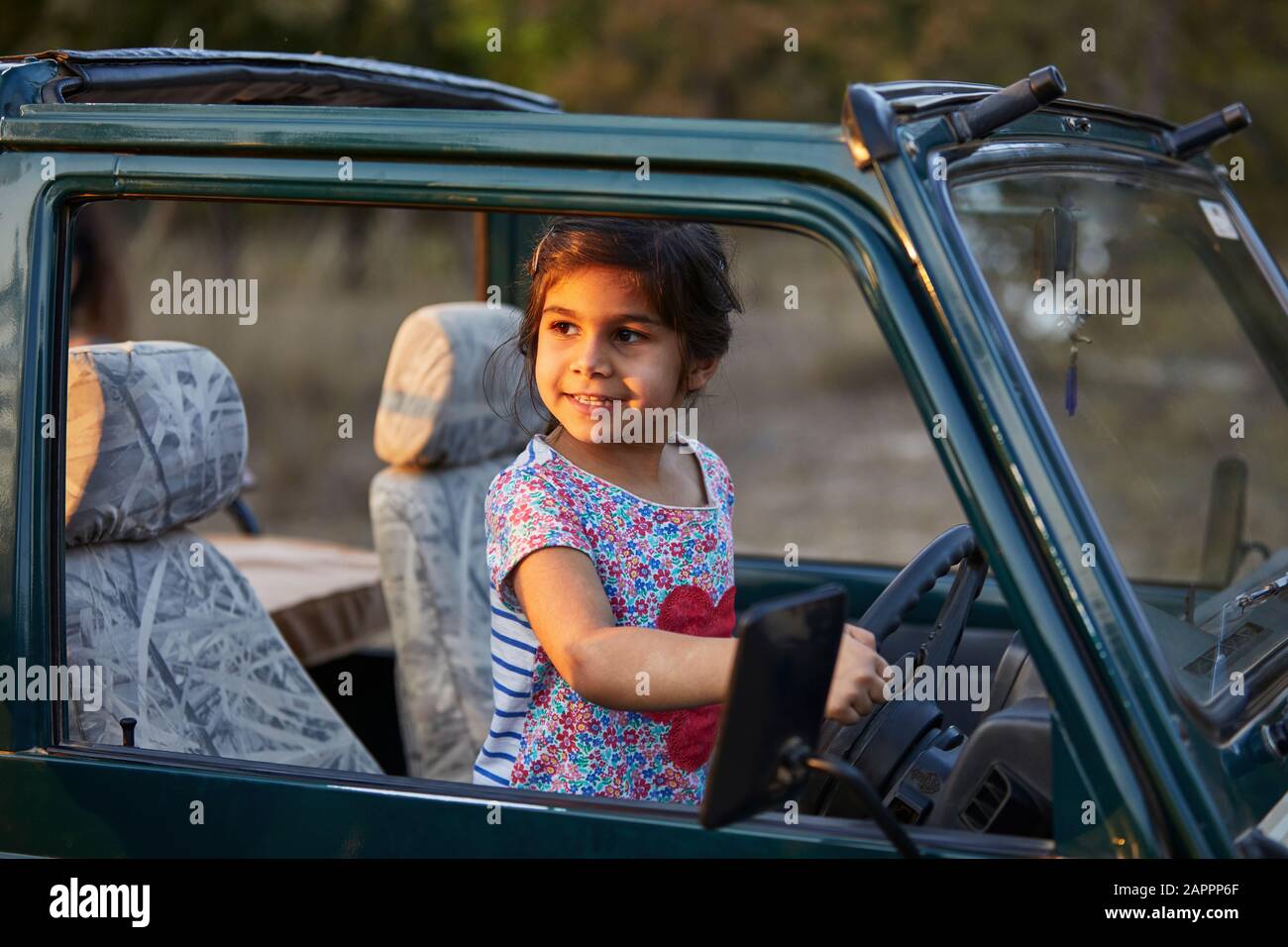 Kleines Mädchen hinter Fahrzeugrädern Stockfoto