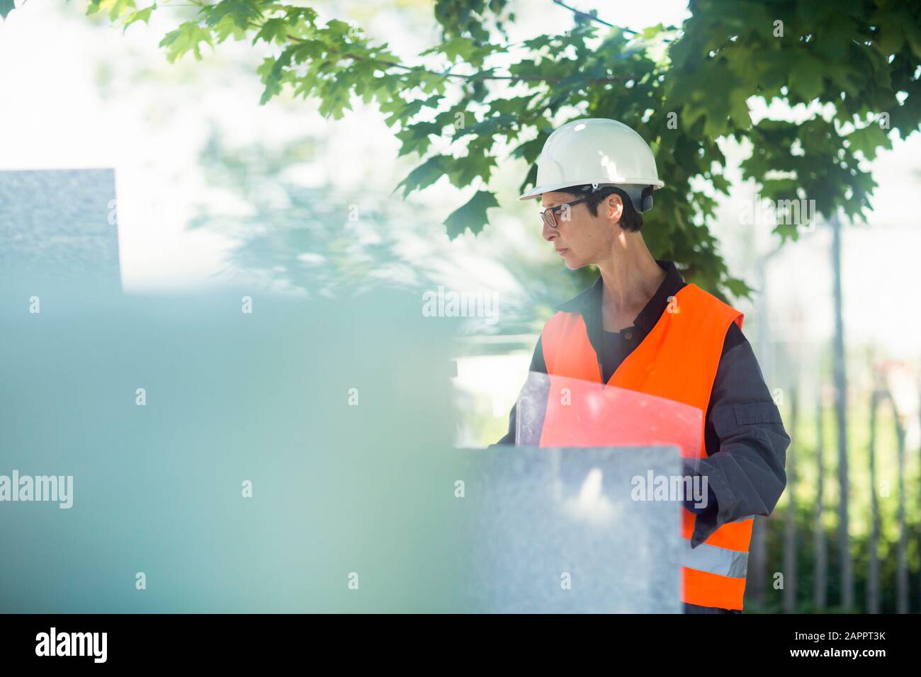 Frau, die im Freien in einer hohen Vis Jacke und einem sicheren Schutzhut arbeitet. Stockfoto