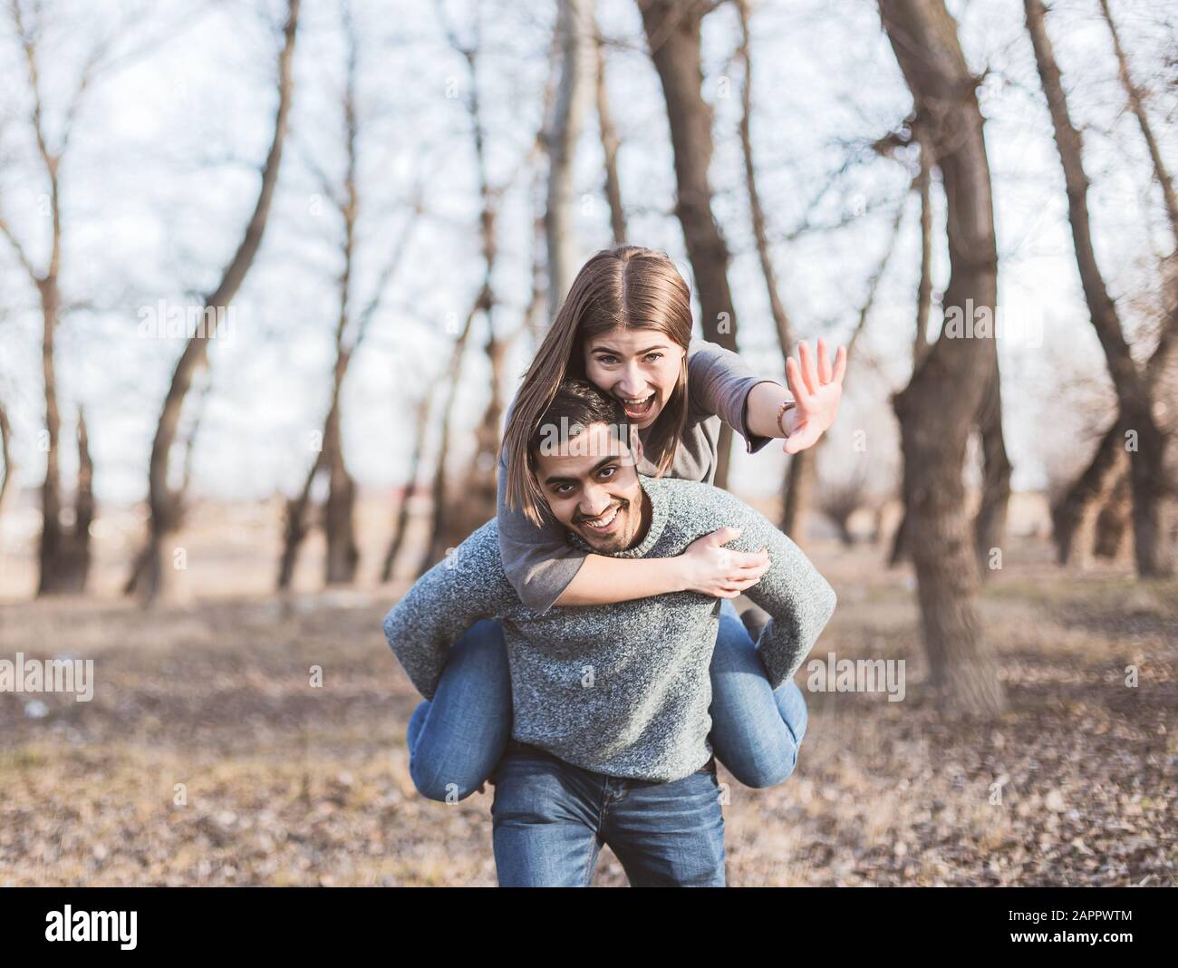 Fröhliches junges fröhliches Paar, das im Herbst Spaß am Huckepack hat, zusammen zu lachen Stockfoto