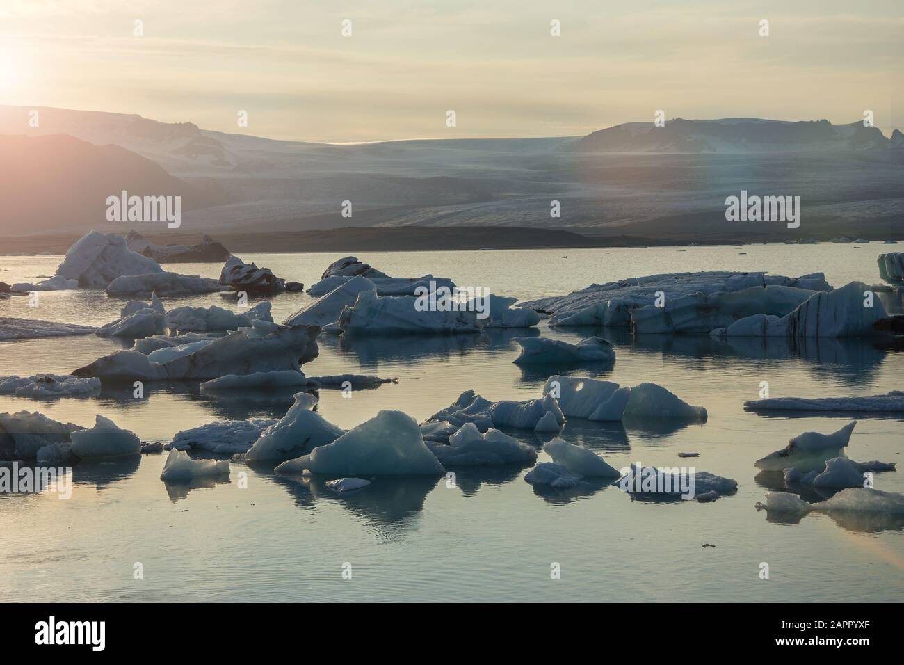 Eisberge in der Gletscherlagune Jökulsárlón während einer pulsierenden roten Sonnenuntergang liegt bewegungslos, wie es ist umrahmt von einer kalten Ozeanwasser. Stockfoto