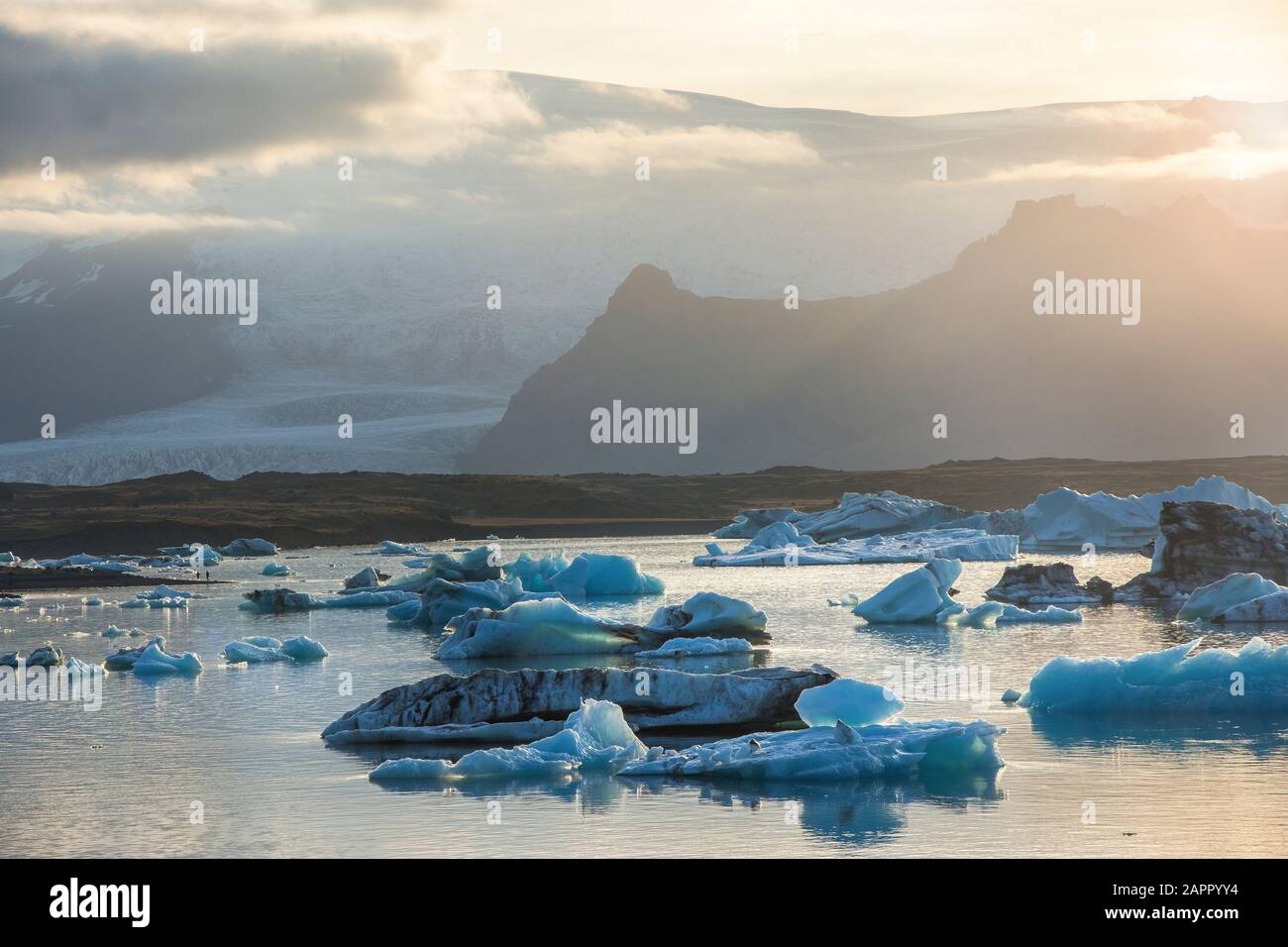 Eisberge in der Gletscherlagune Jökulsárlón während einer pulsierenden roten Sonnenuntergang liegt bewegungslos, wie es ist umrahmt von einer kalten Ozeanwasser. Stockfoto