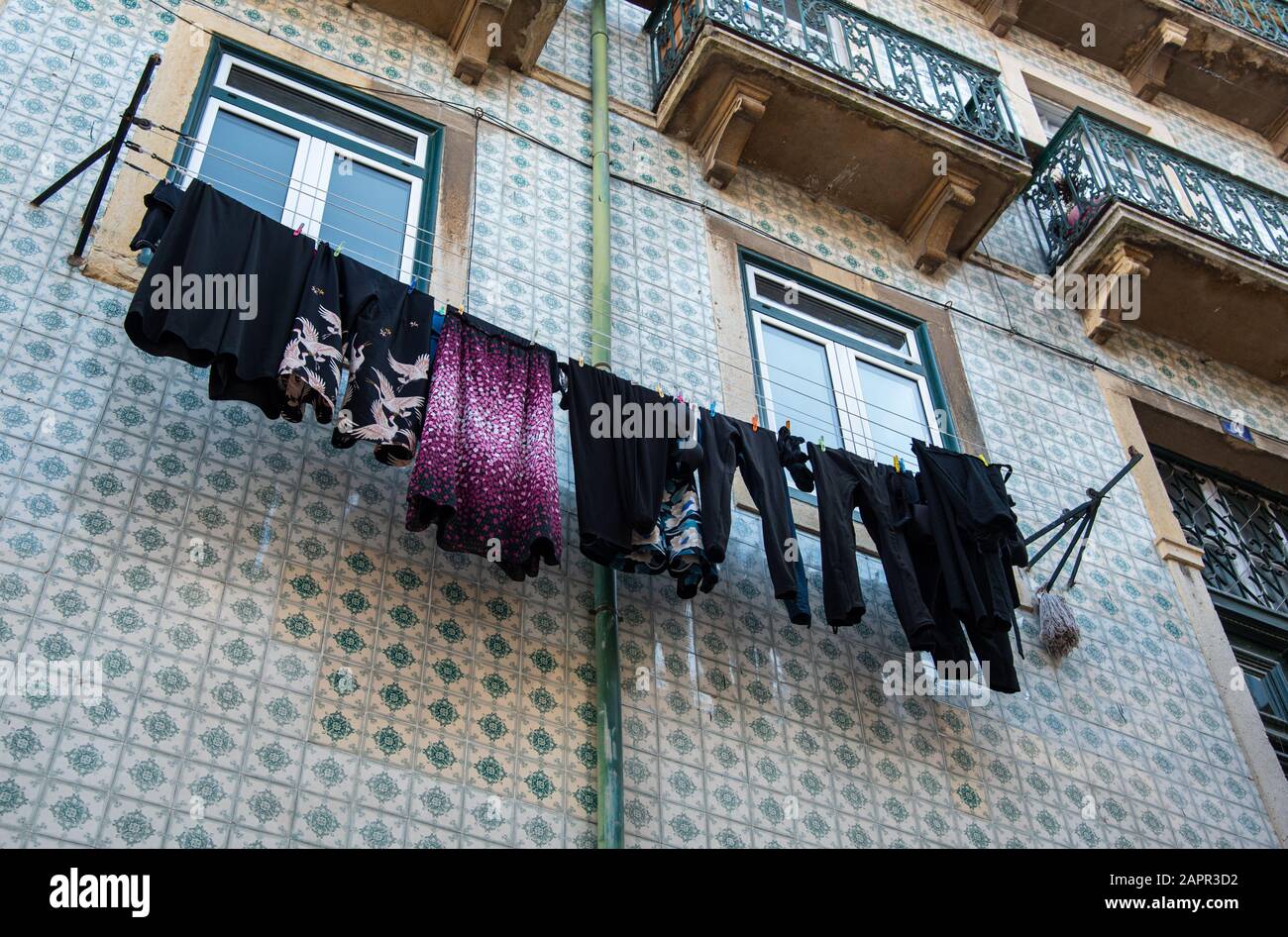 Hauswäsche mit farbenfroher Kleidung, die an einem Seil vor einem Haus zum Trocknen hängt. Stockfoto