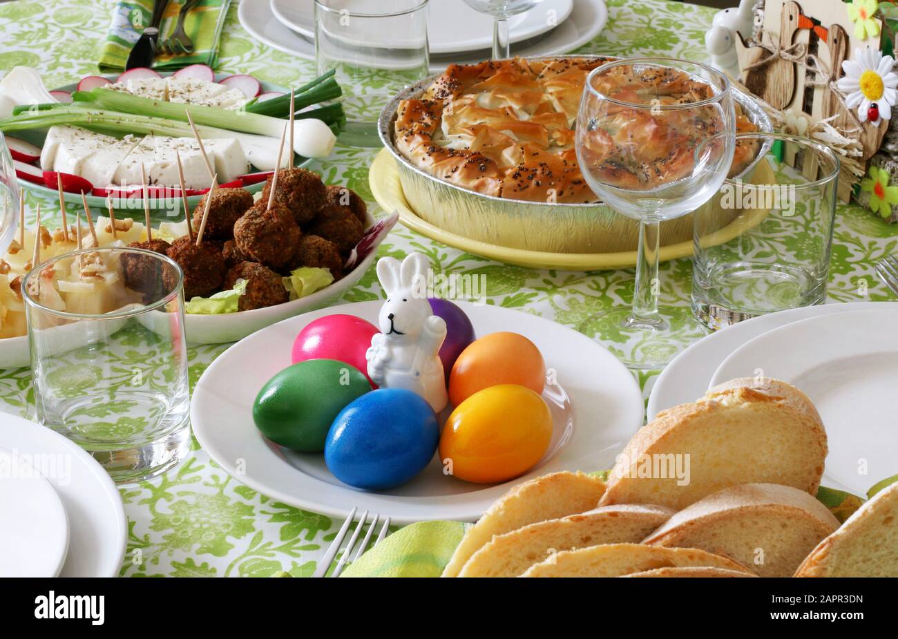 Konzept Frühlings-Feiertag.Ostertischdekoration. Eierkorb, Frühlingsblumen und bunte Einrichtung. Brot, Käse, Spinatkuchen, Fleischkugel, Gemüse. Stockfoto