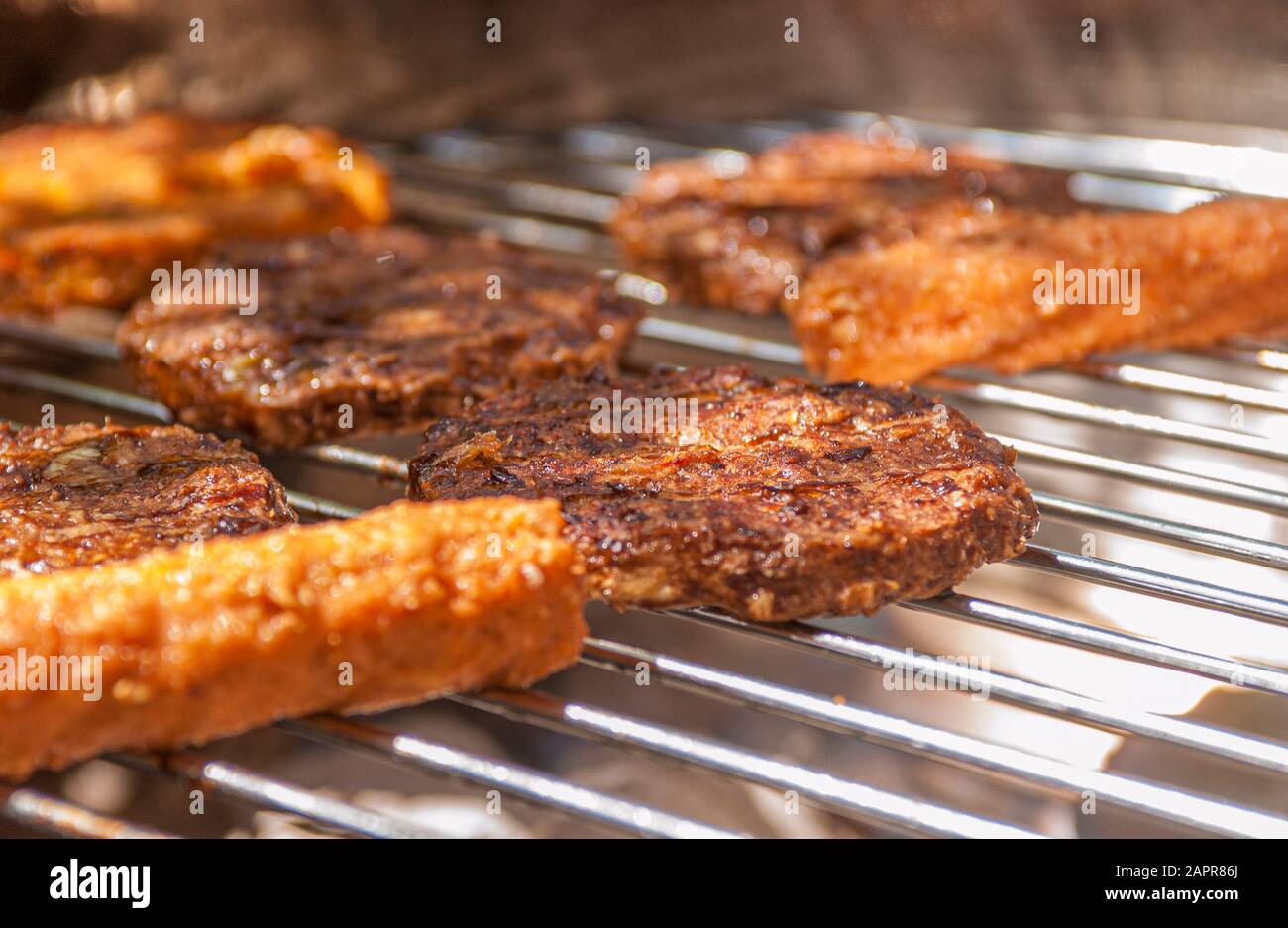 Burger und Würstchen, die draußen auf dem Grillgrill aus Chrom kochen Stockfoto