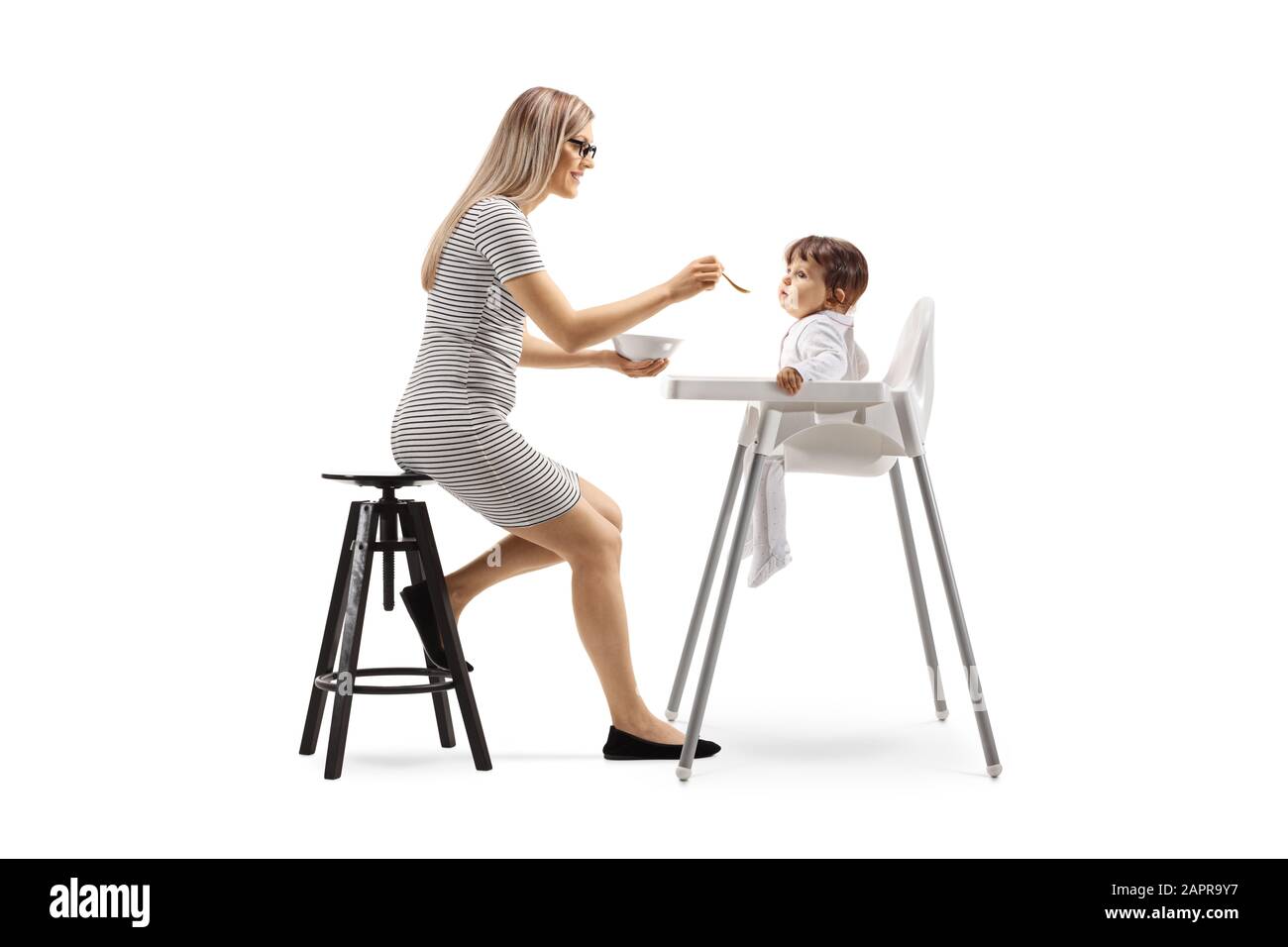 Lange Aufnahme einer Mutter, die ein Baby in einem Stuhl füttert, der auf weißem Hintergrund isoliert ist Stockfoto