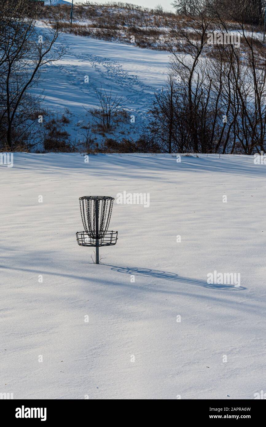 Ein Discgolfkorb wartet auf ein Tauwetter auf einem schneebedeckten Platz in West des Moines, Iowa. Stockfoto