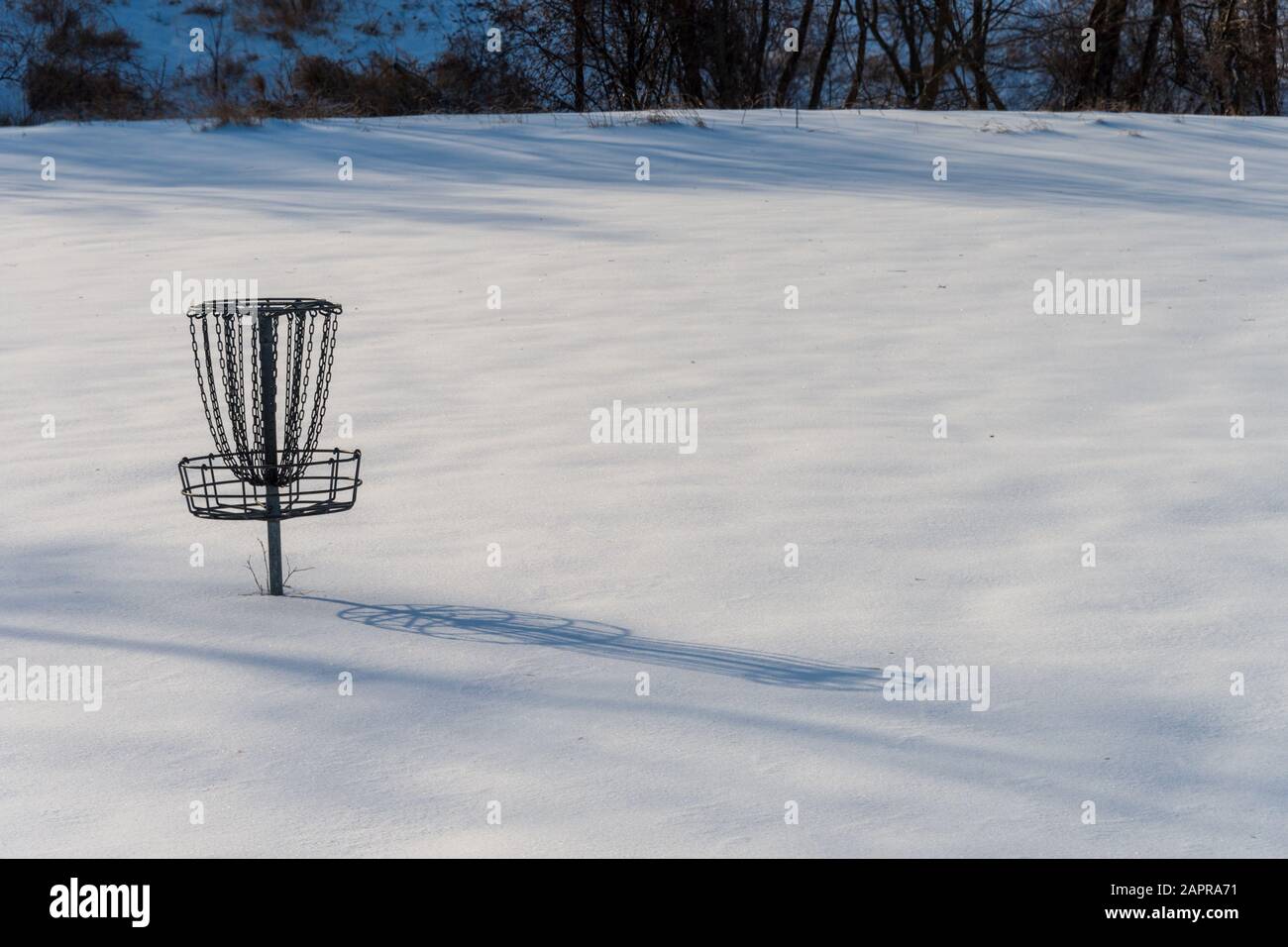 Ein Discgolfkorb wartet auf ein Tauwetter auf einem schneebedeckten Platz in West des Moines, Iowa. Stockfoto