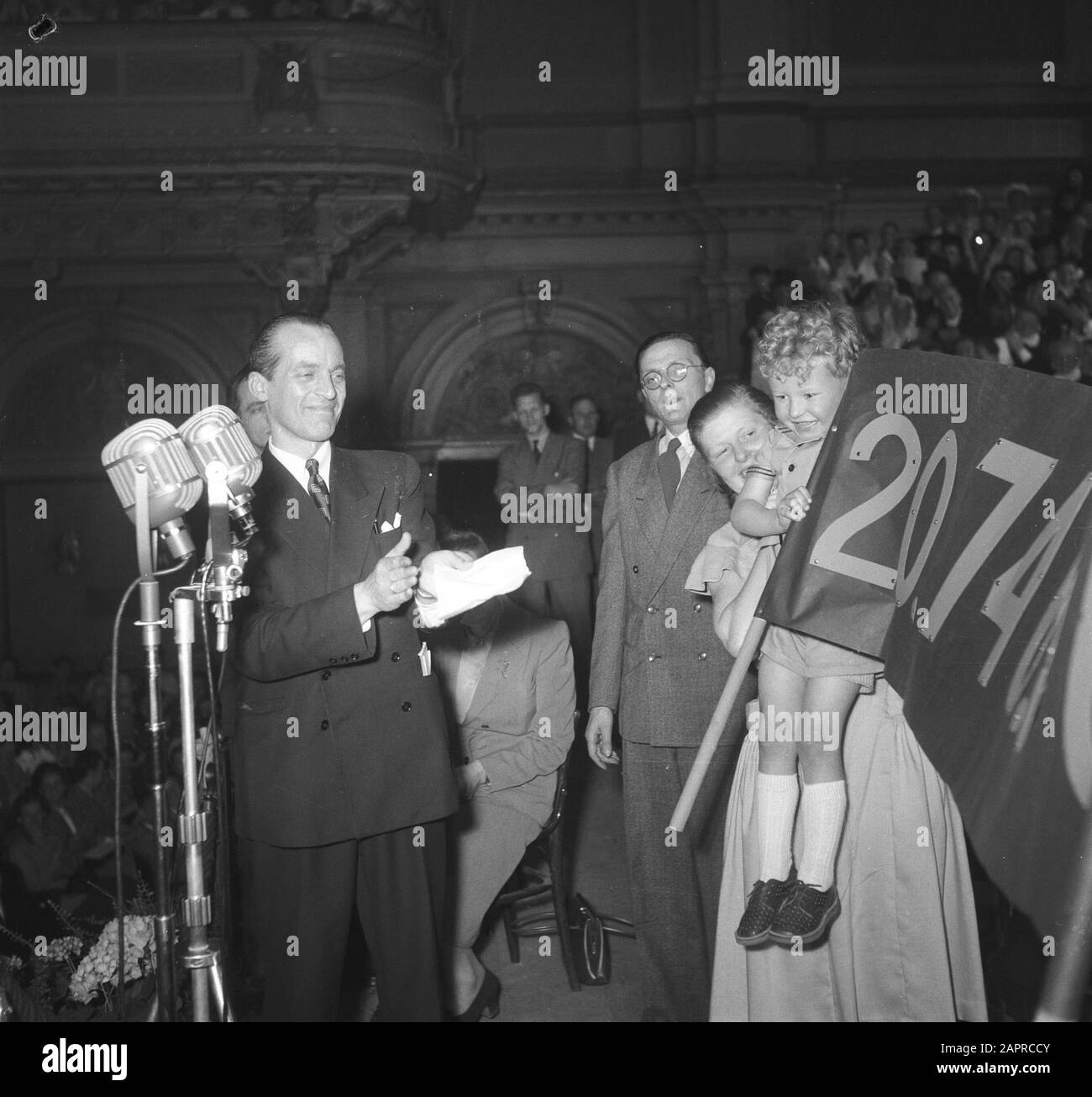 Abschlussabend Haak-In-Aktion im Concertgebouw in Amsterdam. Moderator Johan Bodegraven lobt ein Banner mit dem Erlös der Kindergartensammlung Annotation: NCRV-Aktion für den KWF-Krebskampf. Ausgestrahlt im Radio Datum: 24. Mai 1951 Ort: Amsterdam, Noord-Holland Schlüsselwörter: Aktionen, Radioprogramme persönlicher Name: Bodegraven, Johan Stockfoto