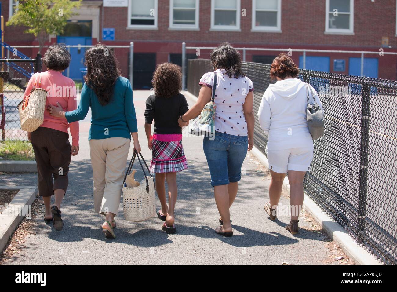 Eine Gruppe von Frauen über drei Generationen, die zusammen in Eine Reihe einen Gehweg im Freien hinunter Stockfoto