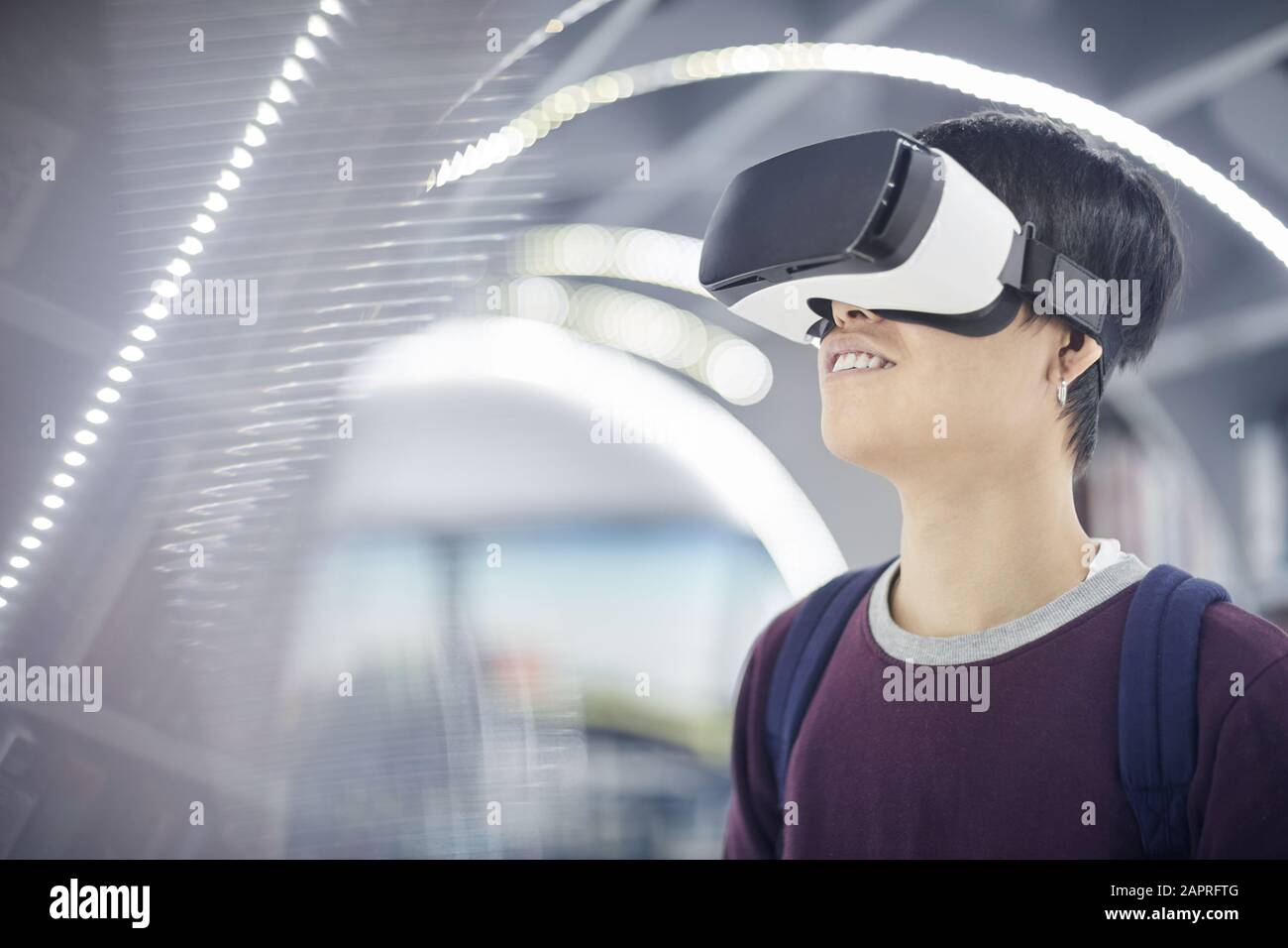 Junger Mann mit Rucksack hinter dem Rücken, der eine intelligente Brille trägt und im Videospiel spielt Stockfoto