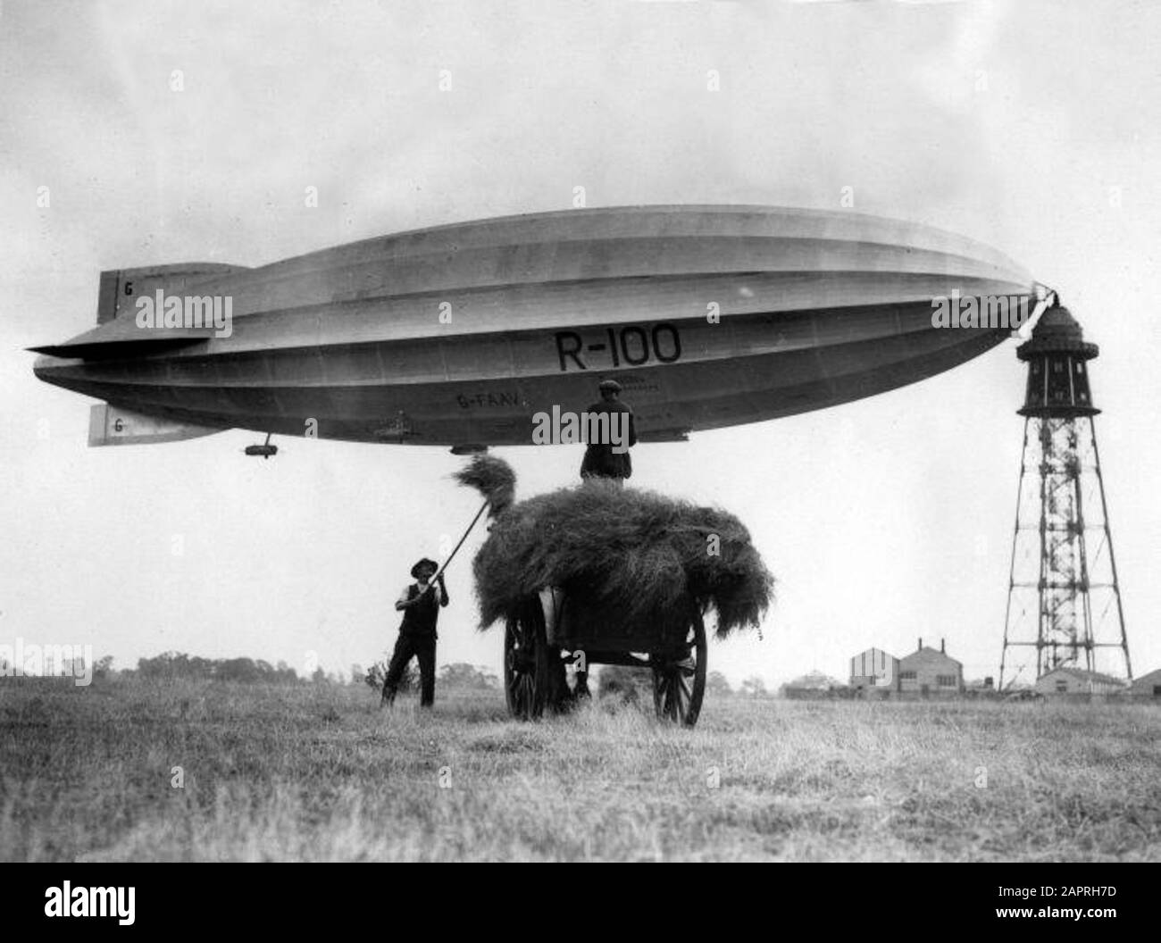 Das englische Luftschiff/[zeppelin] R-100 auf dem Landungsmast kurz vor der Fahrt von Bedfordshire nach Kanada, [28. Juli 1930 oder 30. Juli 1928]. Der R-100 hat eine neue Nase und einen neuen Schwanz. Vordergrund: Heu, Heuwagen. Stockfoto