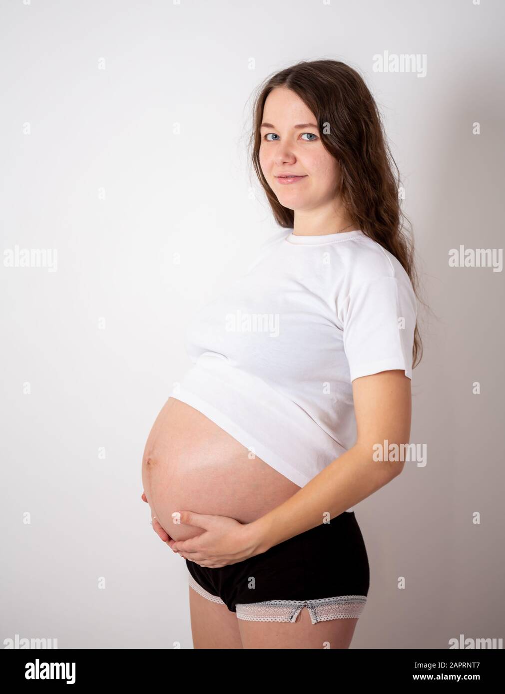 Die junge schöne schwangere Frau erlebt starke Emotionen auf weißem Hintergrund Stockfoto