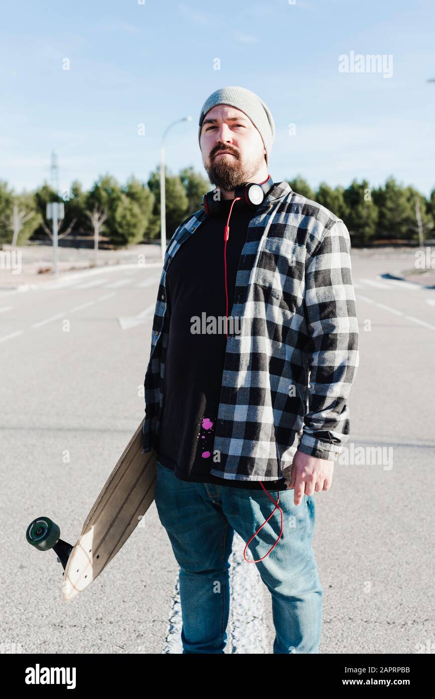 Nahaufnahme eines modernen Mannes, der das Langbrett hält. Skateboarding-Konzept. Stockfoto