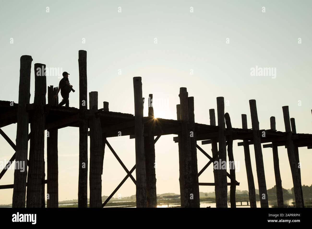 Silhouette des Fotografen, der bei Sonnenaufgang auf der U-bein Brücke spazierengeht Stockfoto