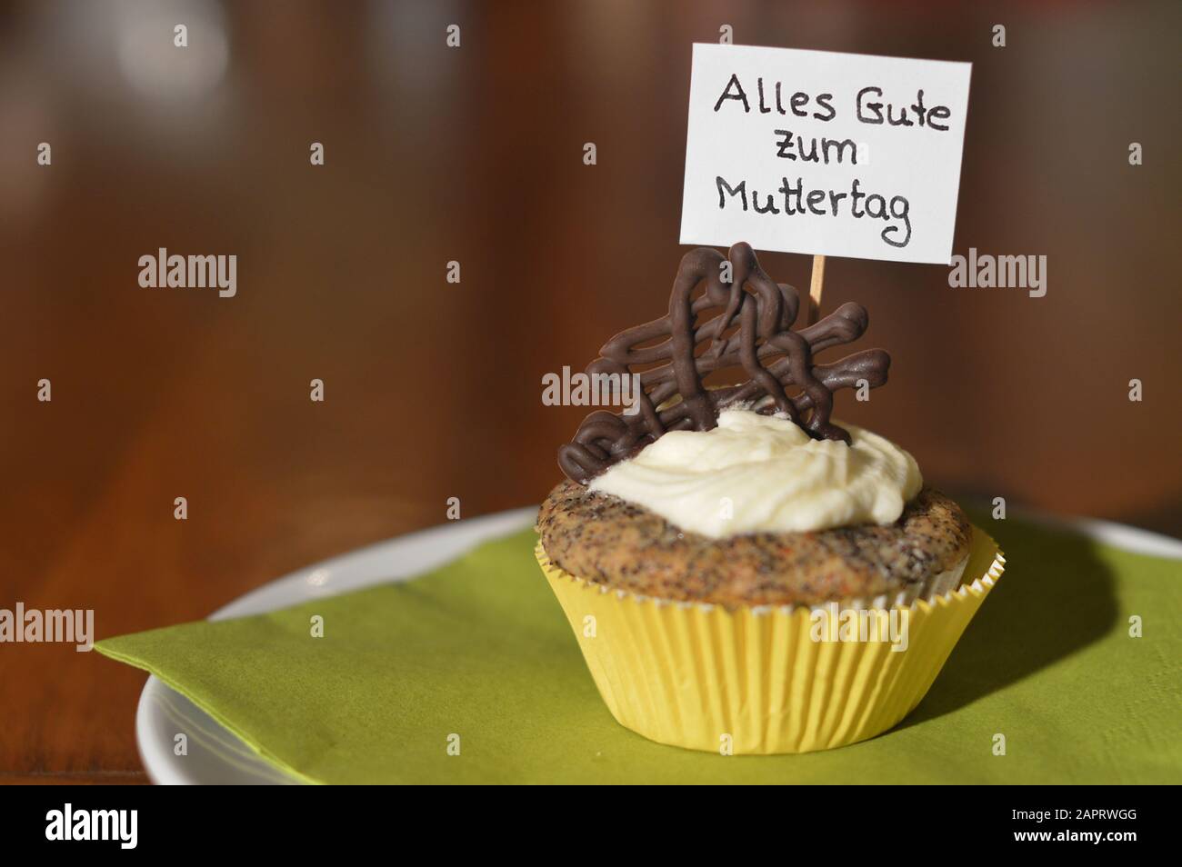 Cupcake mit einem Hinweisschild: Alles GUTE ZUM MUTTERTAG auf Deutsch, was GLÜCKLICHEN MUTTERTAG auf einem Teller bedeutet Stockfoto