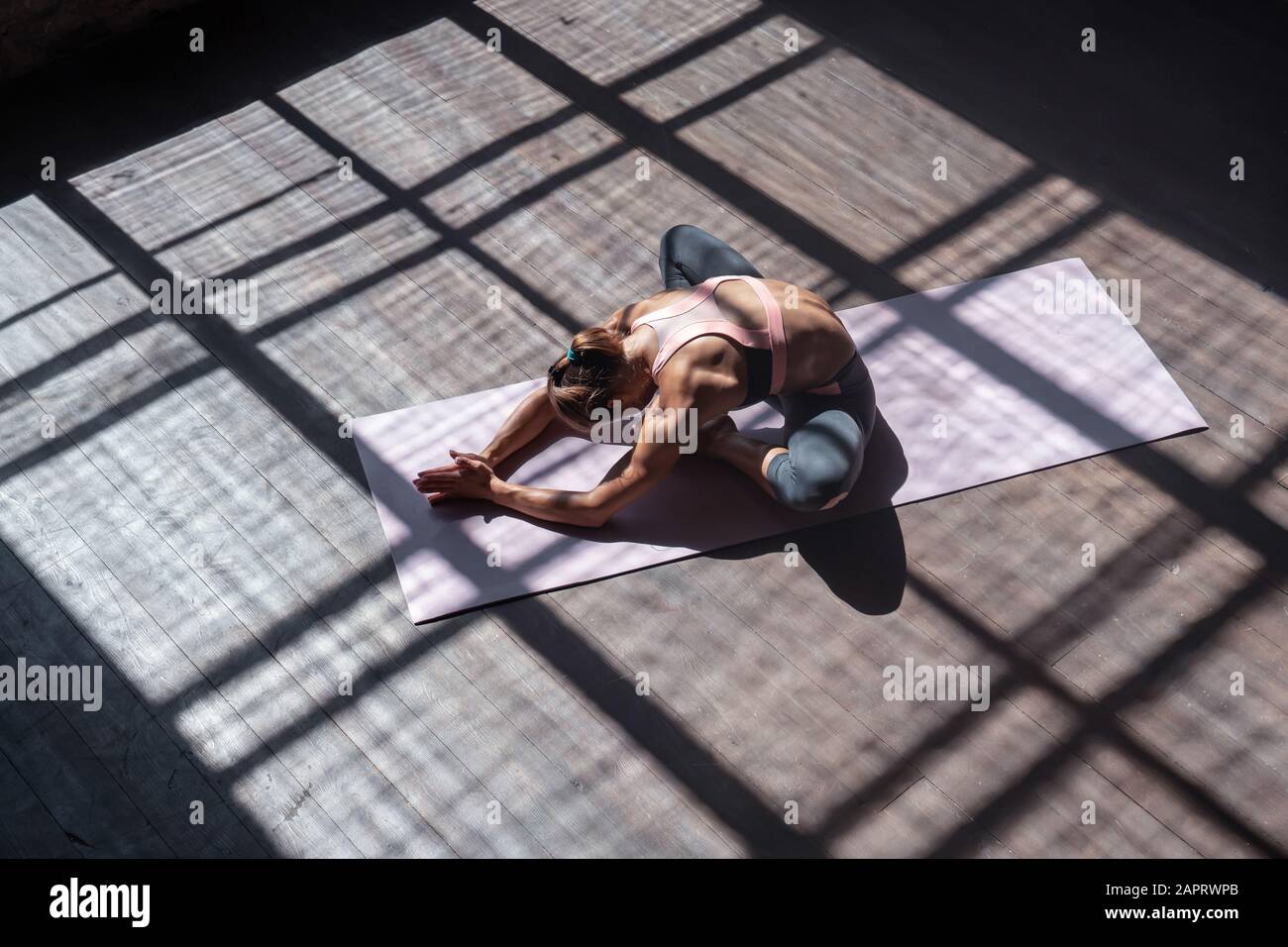Junge Frau übt in der Sporthalle eine mit dem Hatha Yoga gebundene Winkelhaltung, Draufsicht Stockfoto