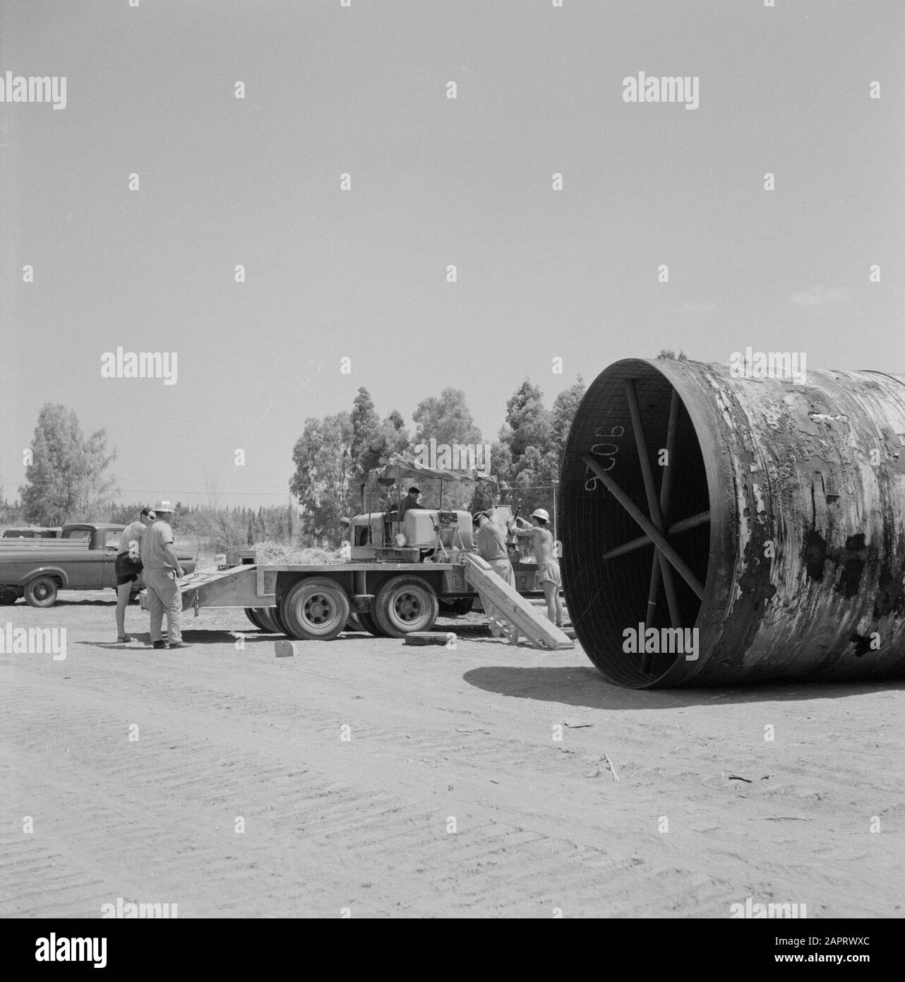 Ein innenliegendem Rohr, das aus einem LKW entrollt wurde, der als Teil eines Bewässerungsprojekts in der Negev-Wüste platziert werden soll Datum: 1. Januar 1960 Standort: Israel, Negev-Schlüsselwörter: Arbeiter, Rohre, Streben, Transport, Lastwagen Stockfoto